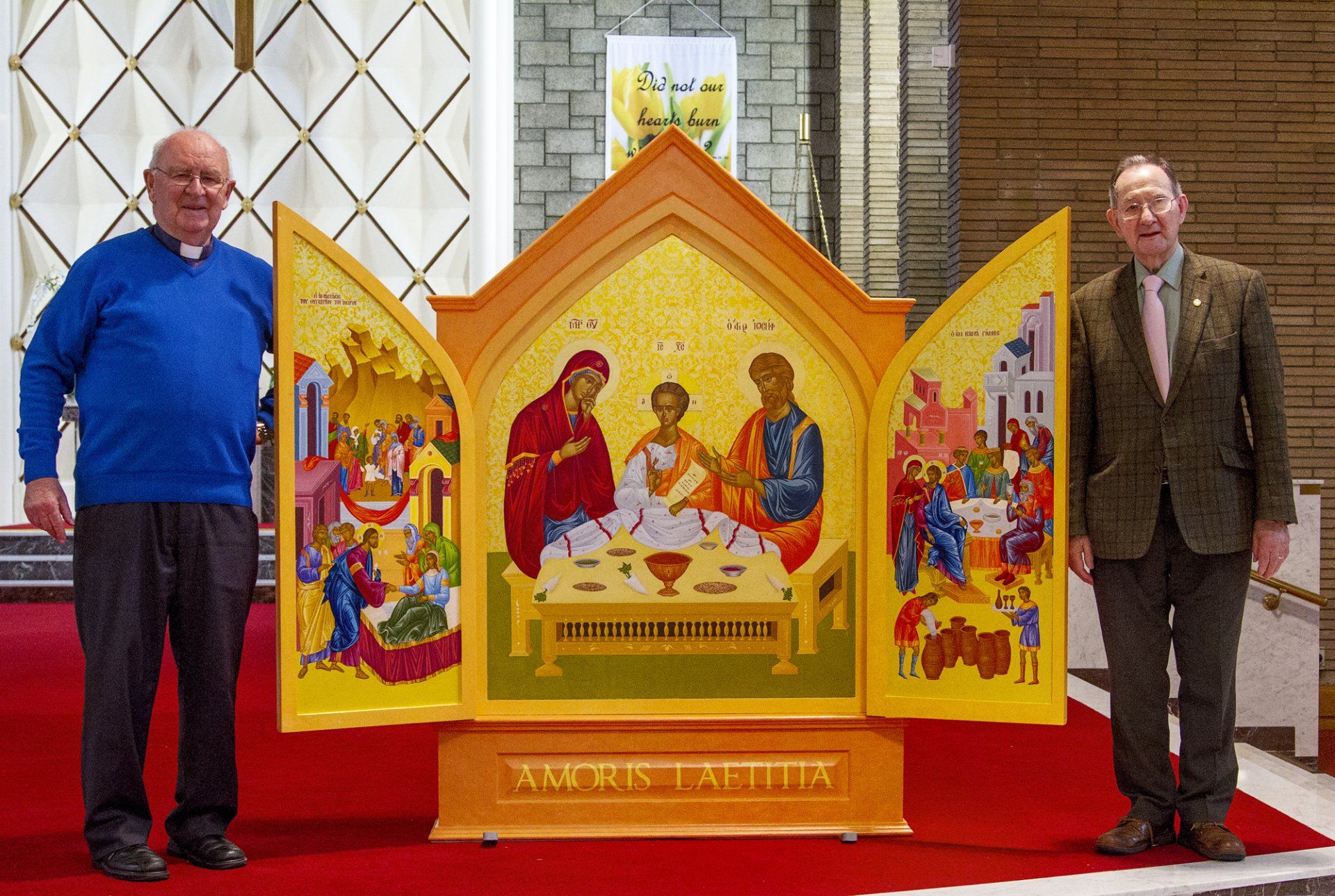 Two men are standing next to a religious icon in a church.