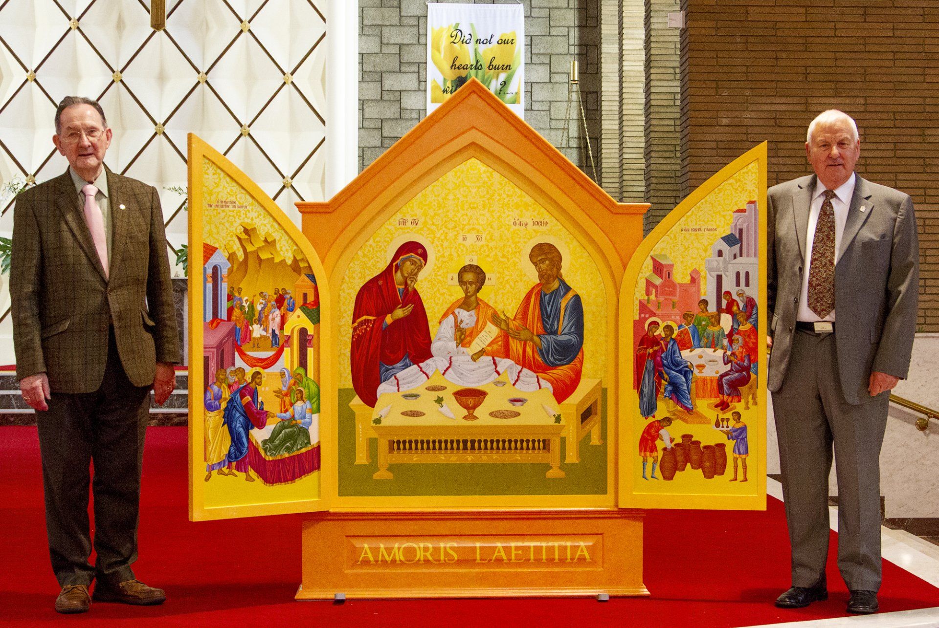 Two men are standing in front of a large religious icon