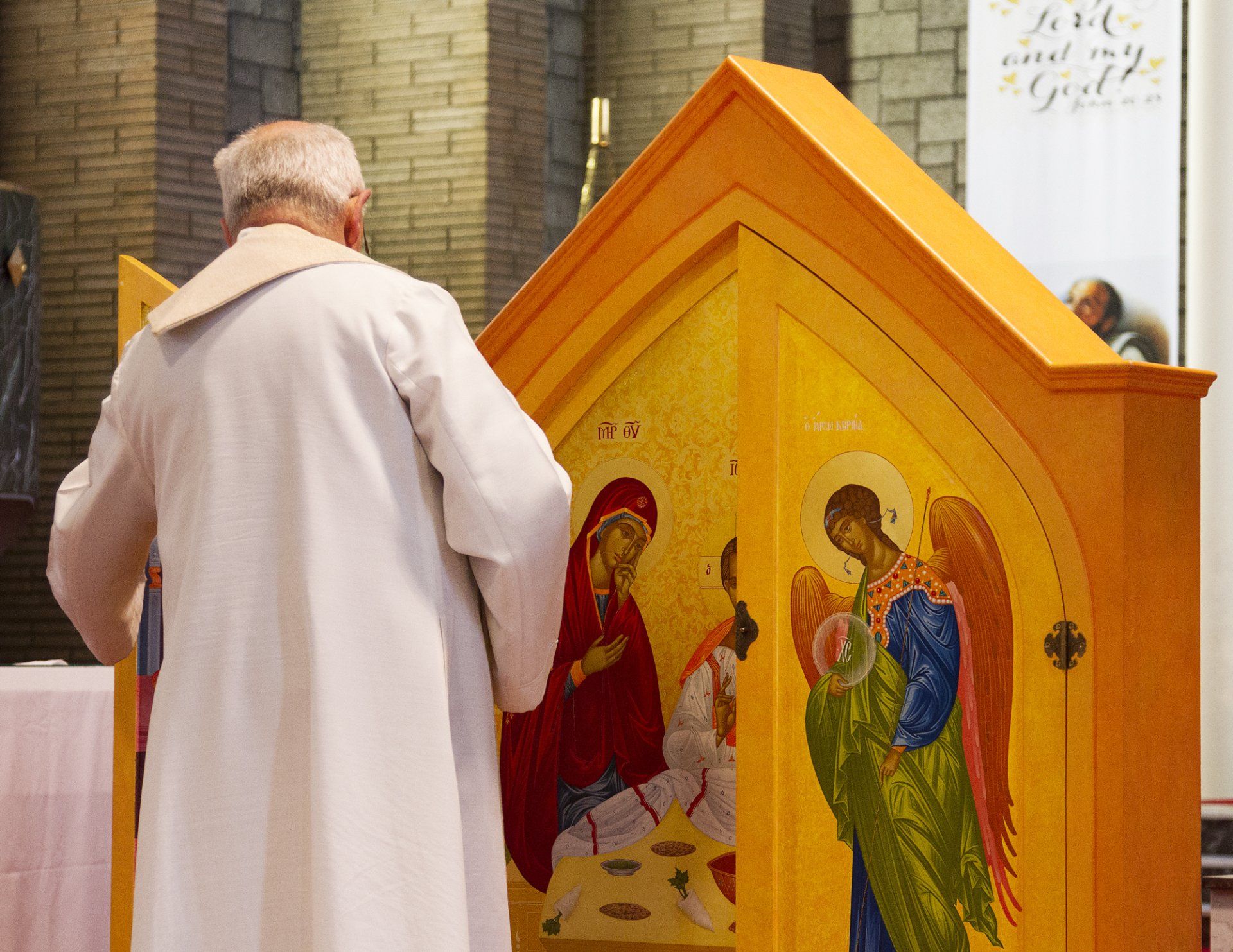 A man in a white robe is looking at a religious icon