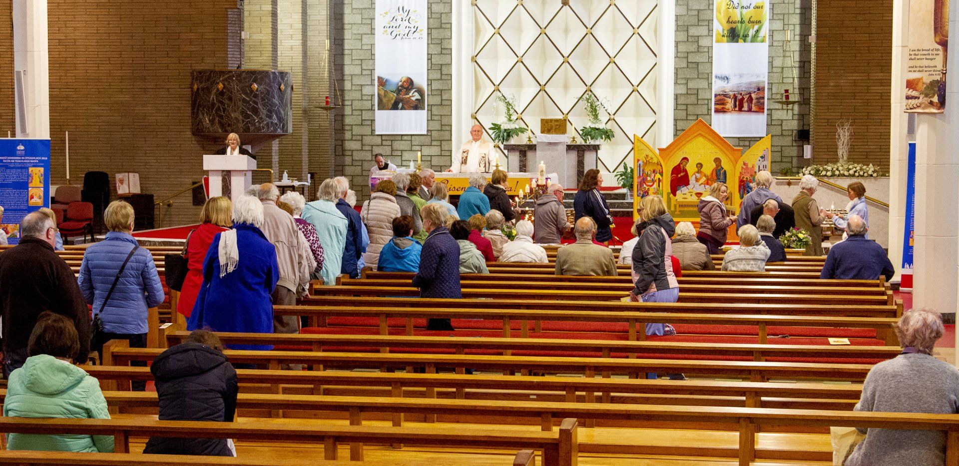 A large group of people are sitting in rows of wooden benches in a church.