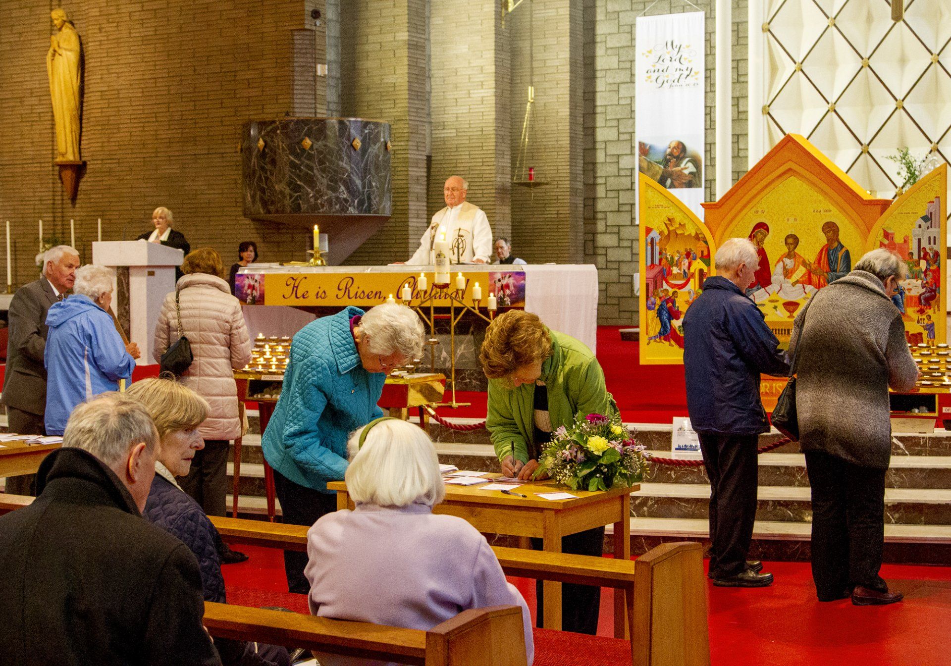 A group of people are gathered in a church looking at a table