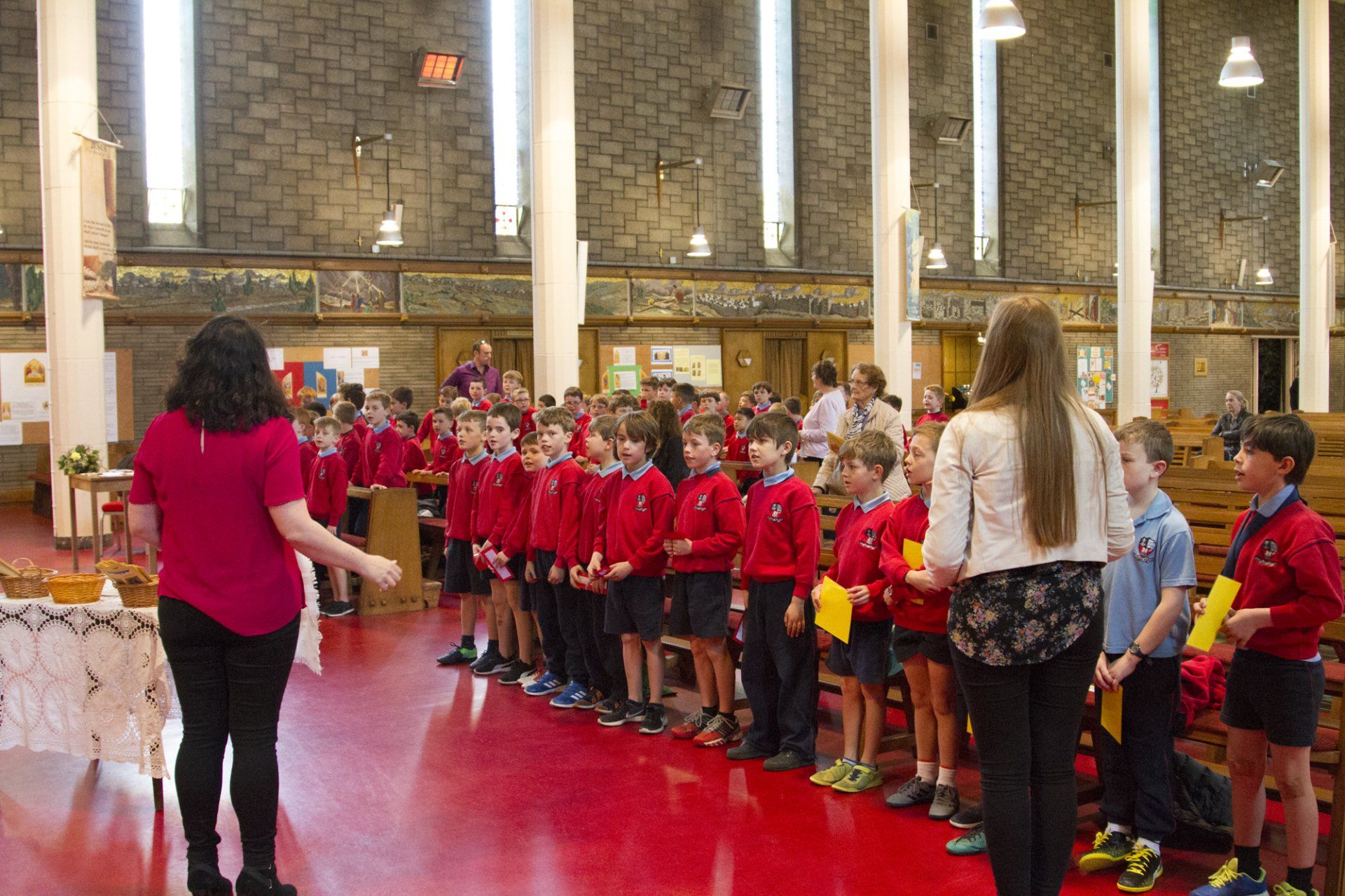 A woman is standing in front of a group of children in a church.