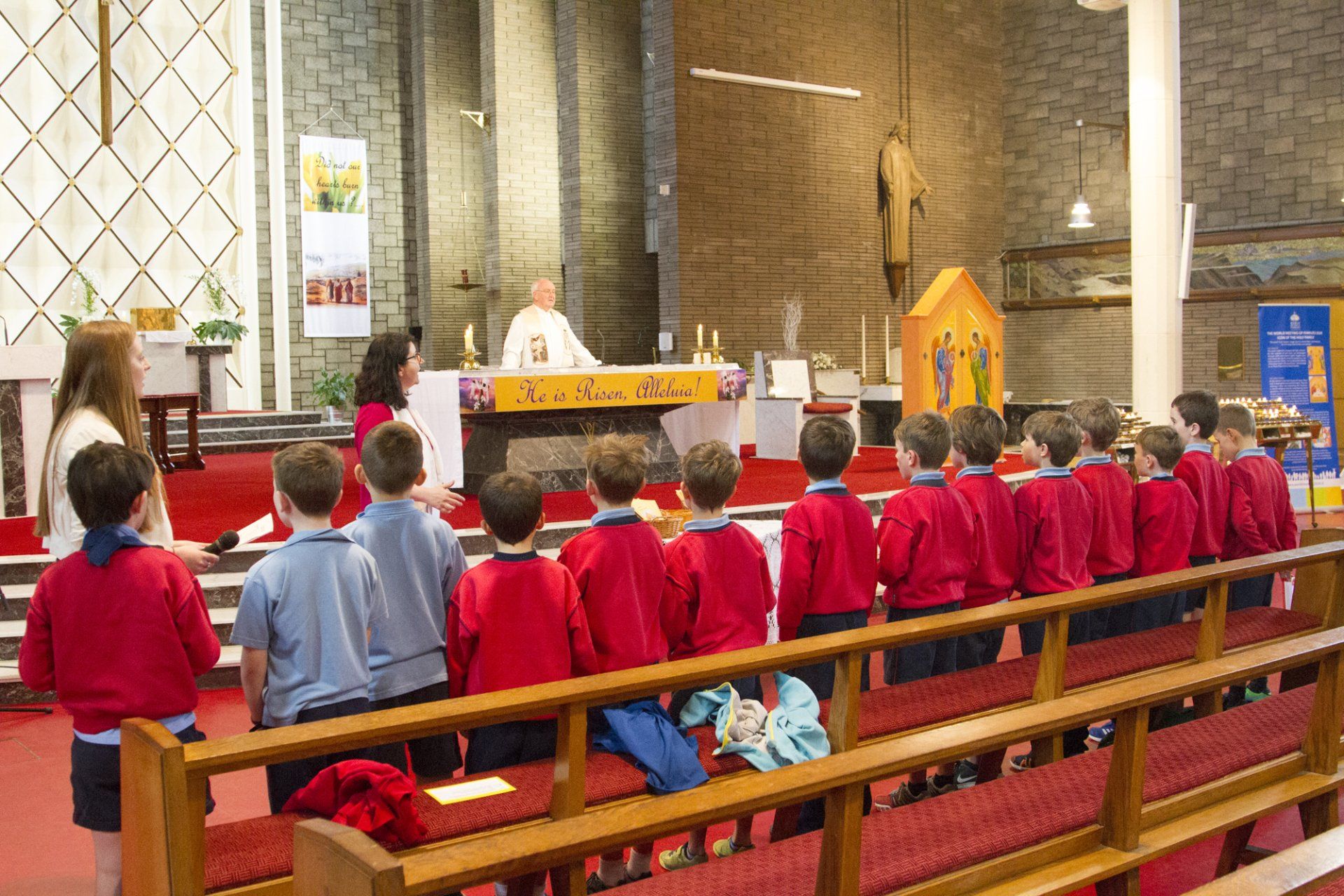 A group of children in red shirts are standing in a church.