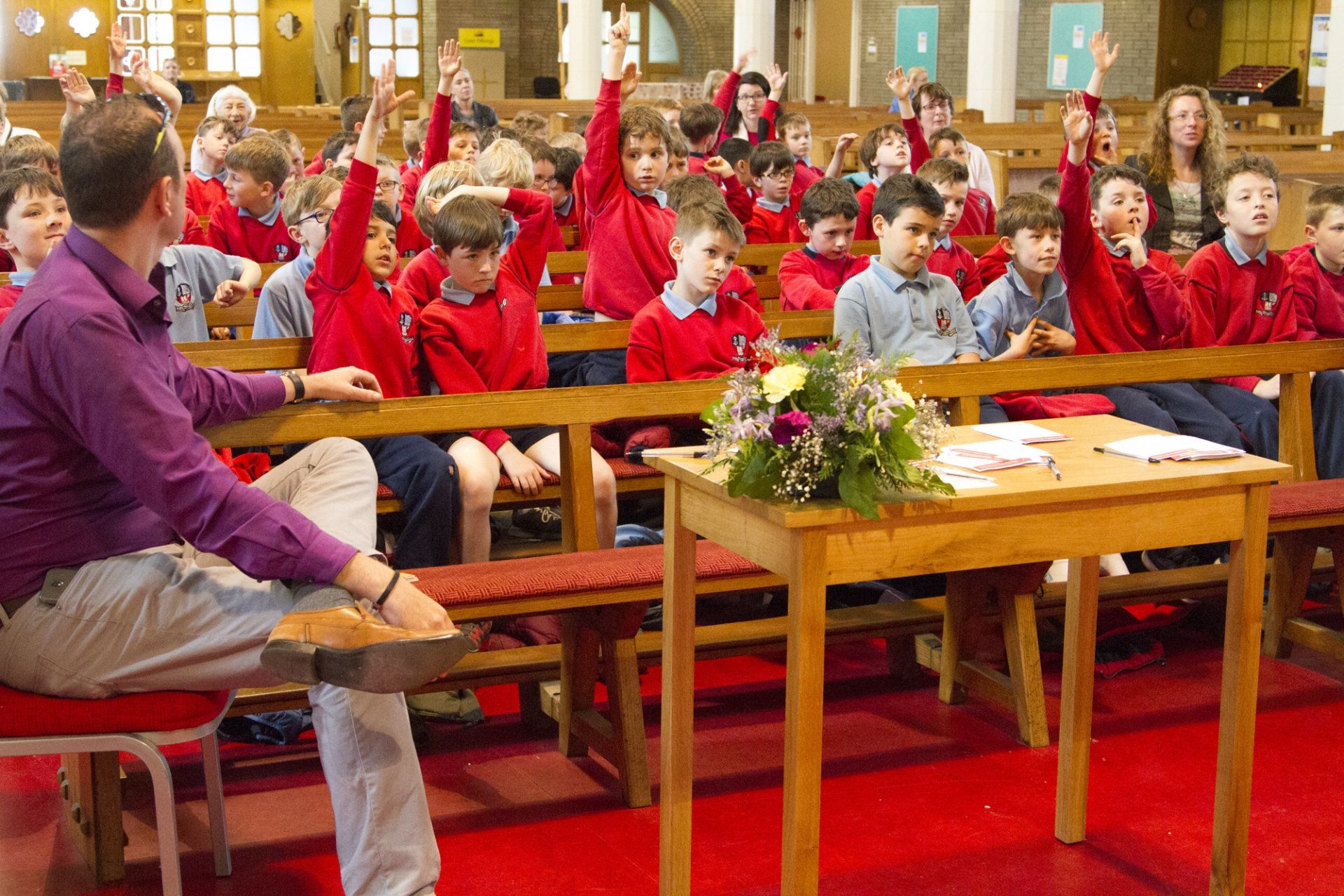 A group of children are raising their hands in a church