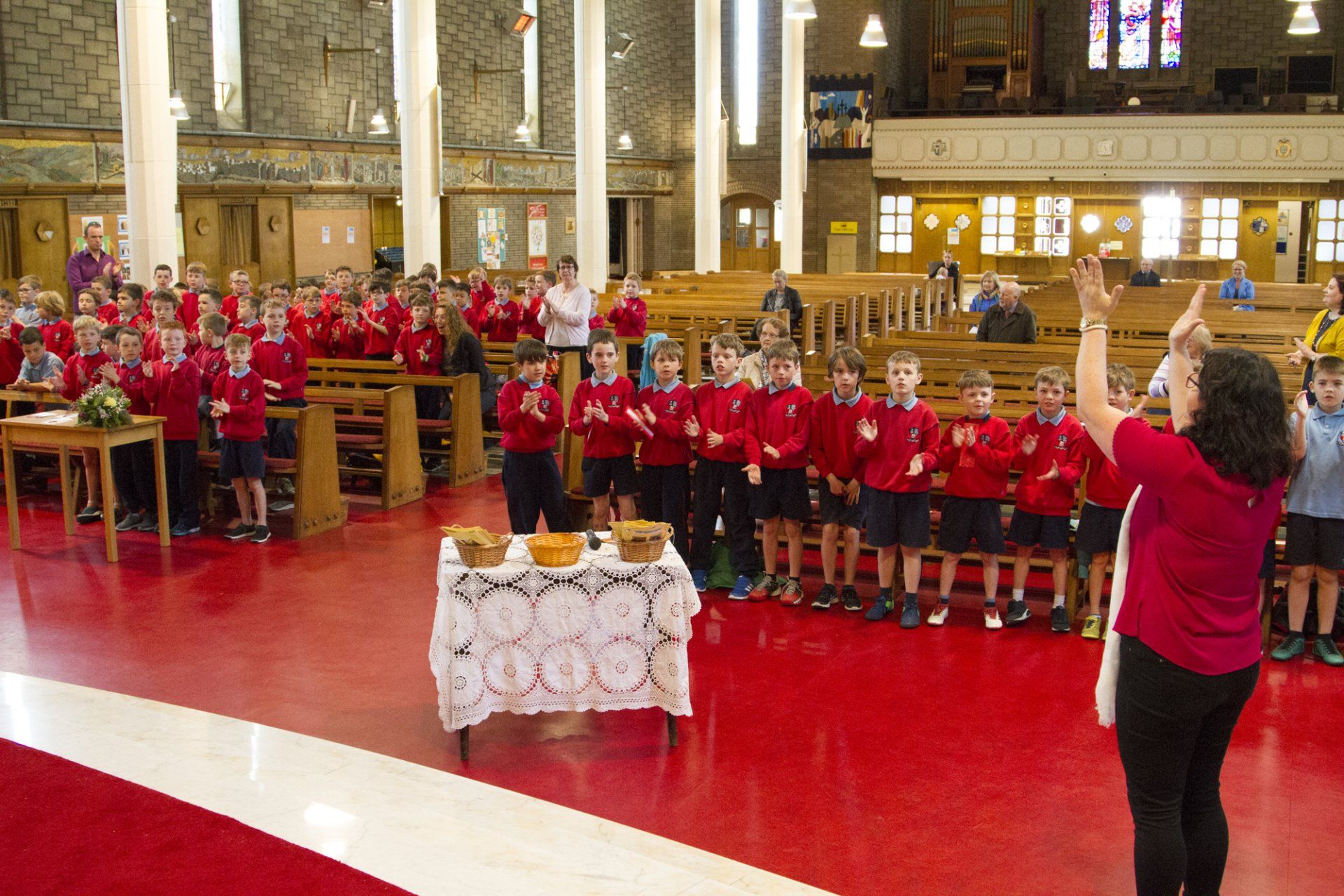 A woman stands in front of a group of children in a church