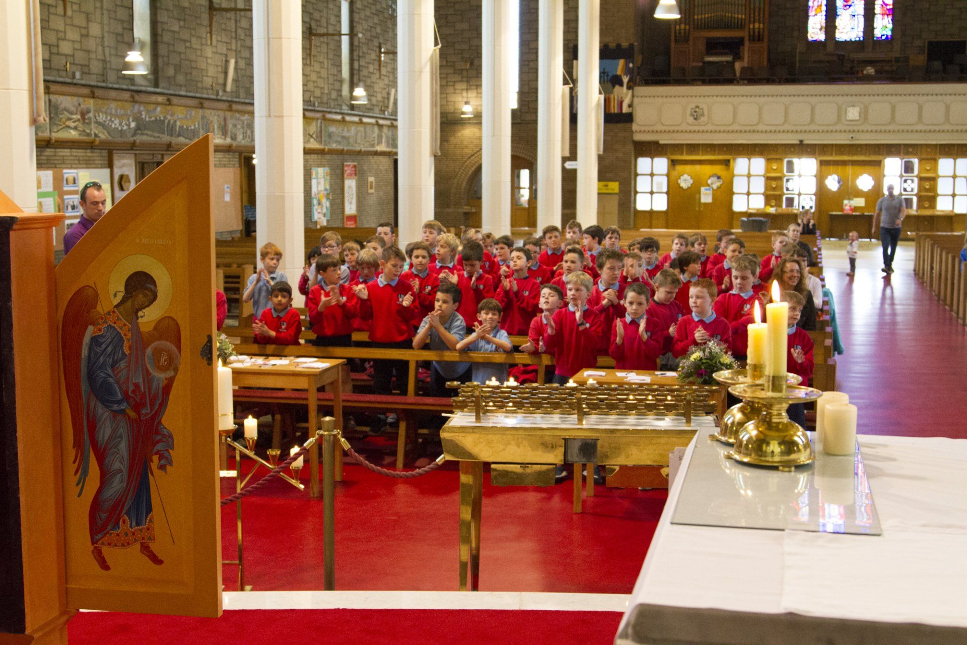 A group of children in red shirts are sitting in a church.