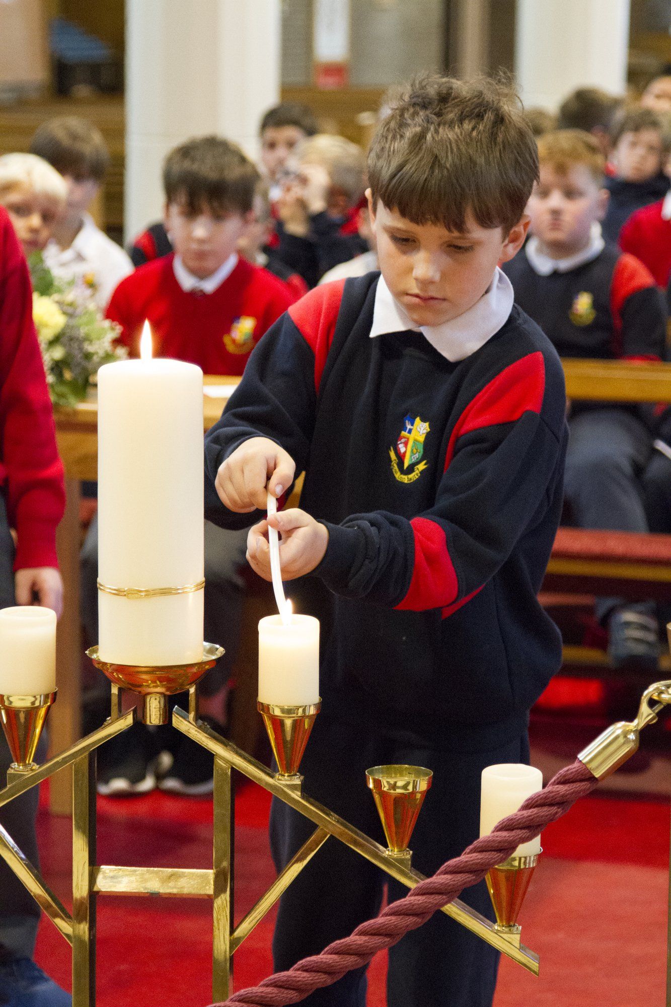 A young boy is lighting a candle in a church