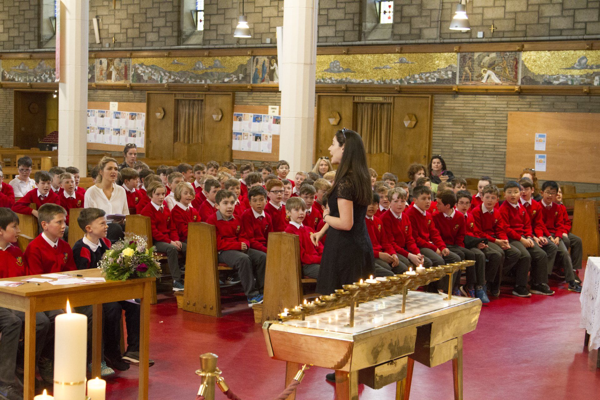 A woman is standing in front of a large group of children in a church.