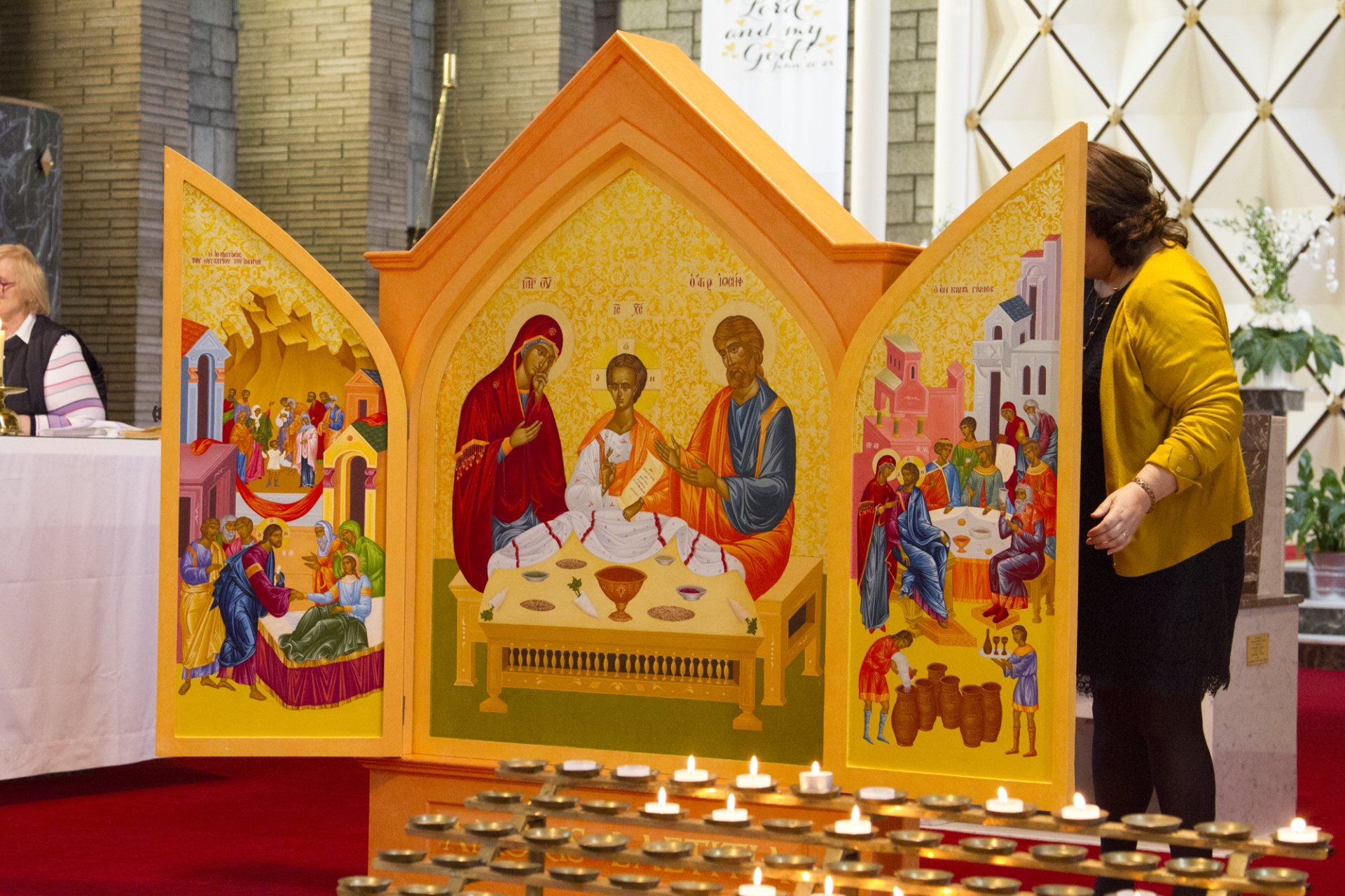 A woman is standing in front of a religious icon in a church.