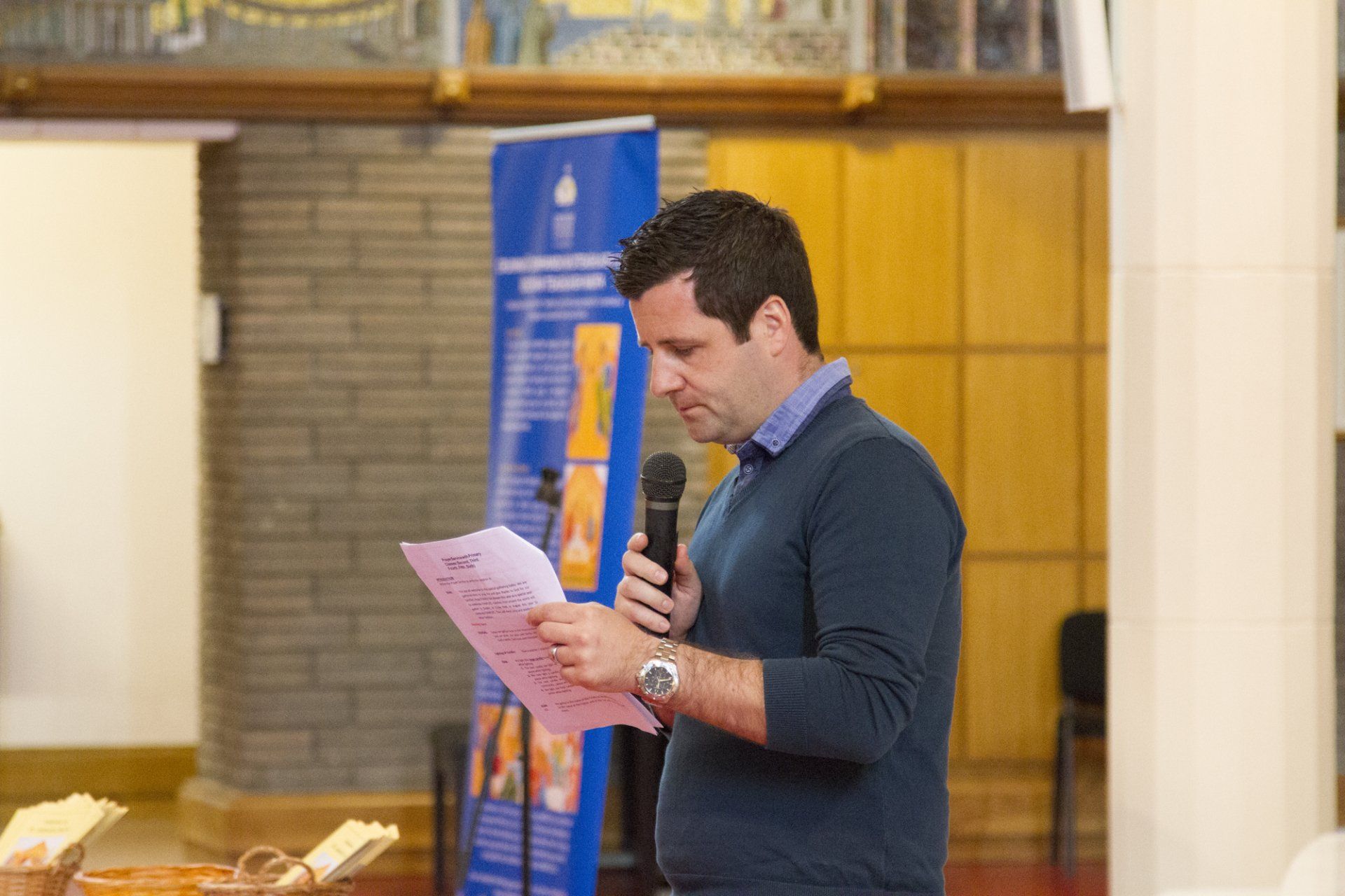 A man is holding a microphone and reading a piece of paper.
