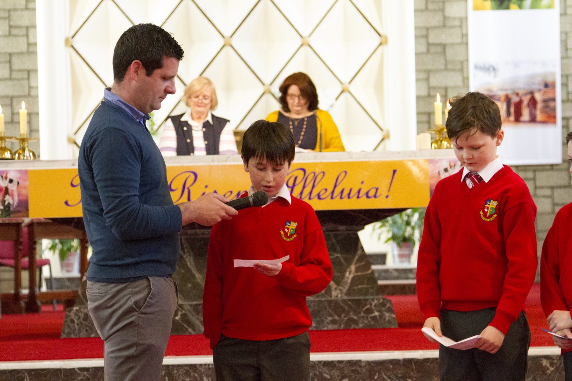 A man is talking to two boys in red sweaters in a church