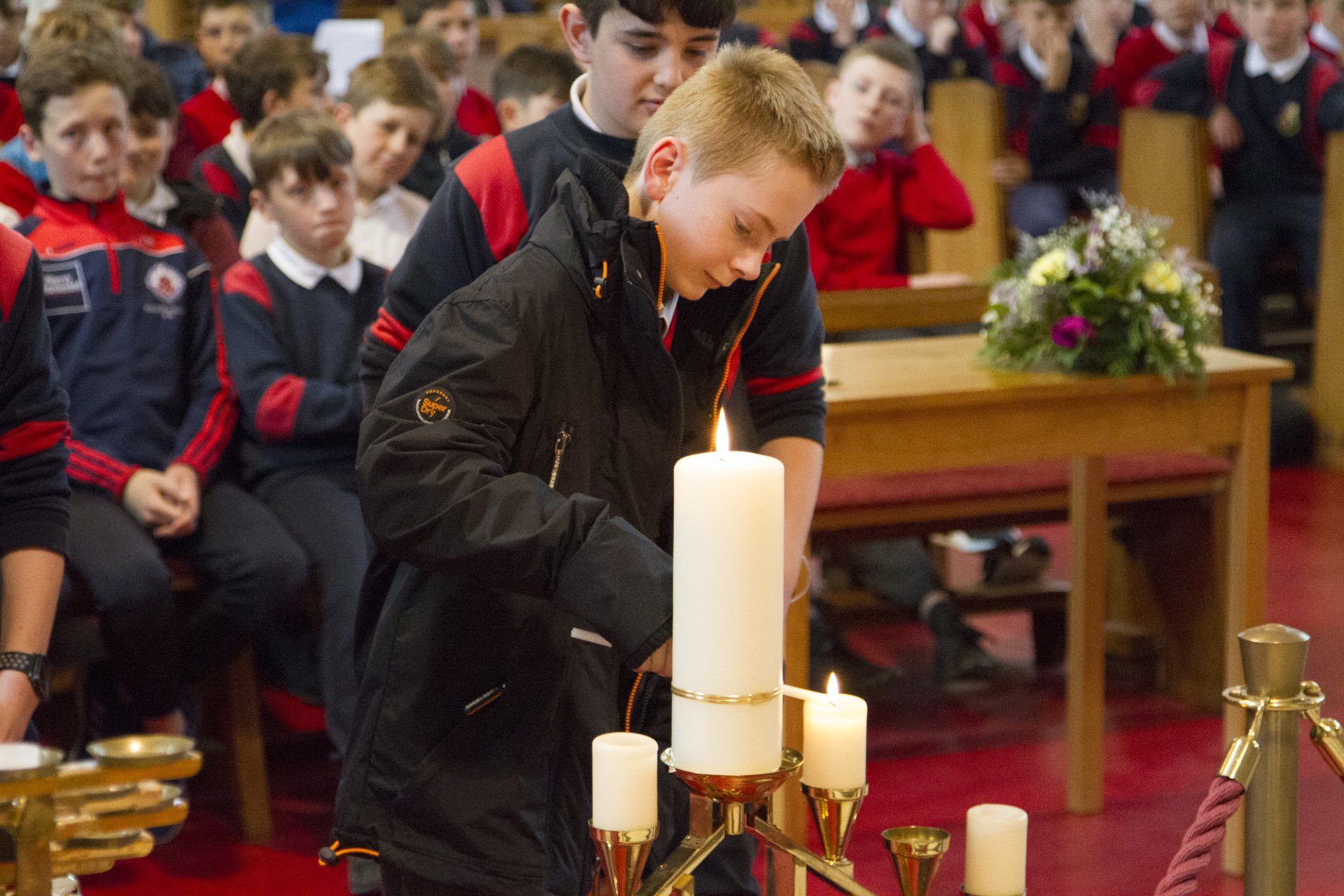 A young boy is lighting a candle in a church.