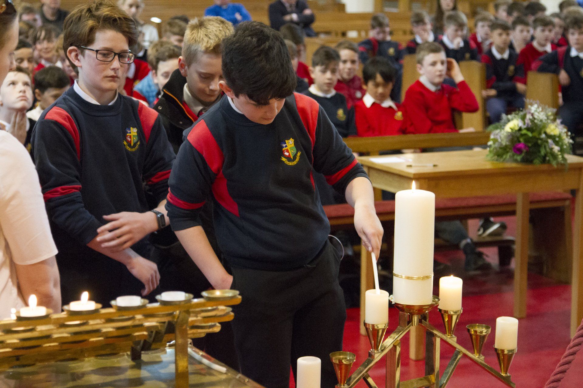 A group of children are lighting candles in a church.