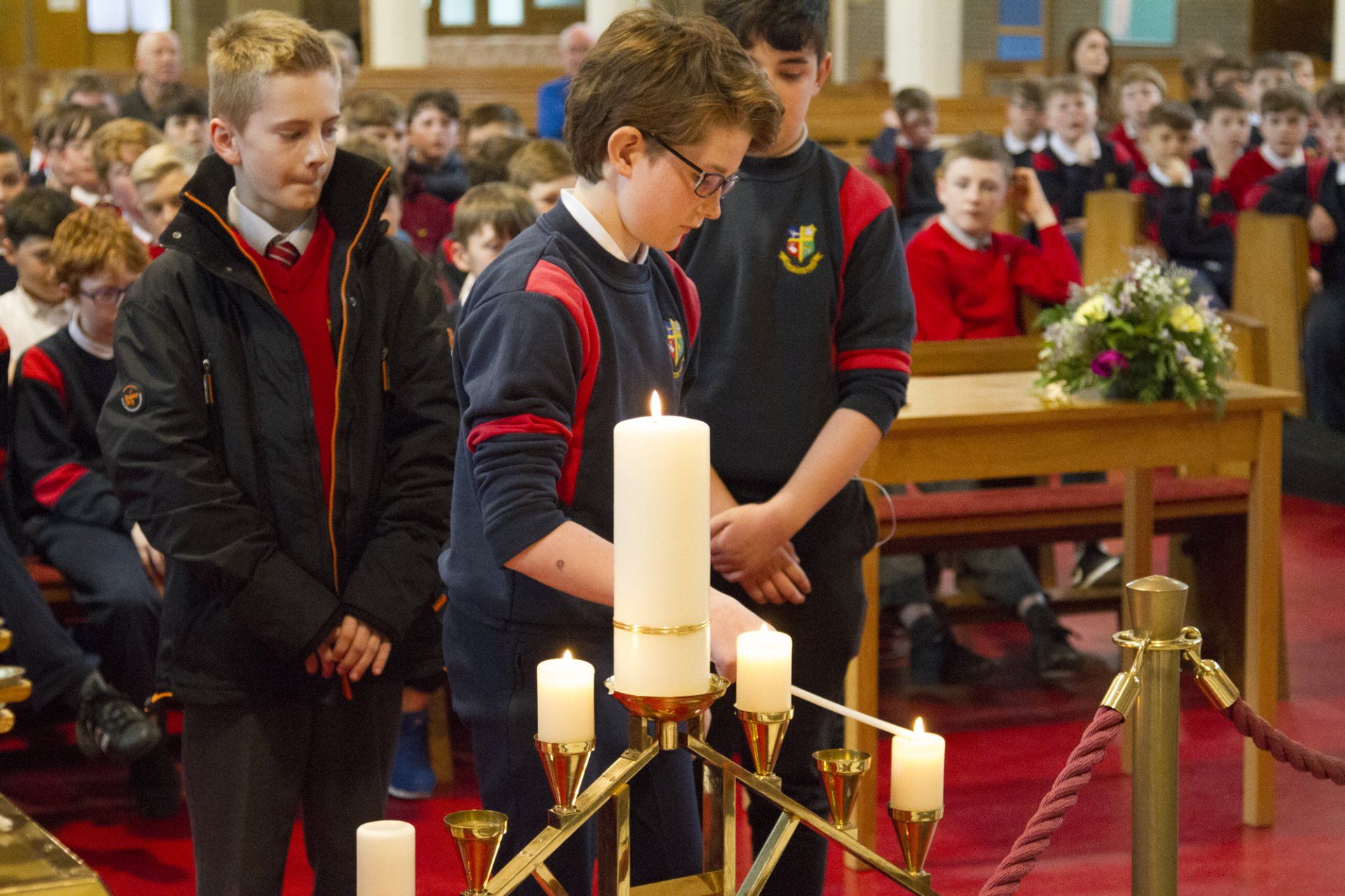 A group of young boys are lighting candles in a church.