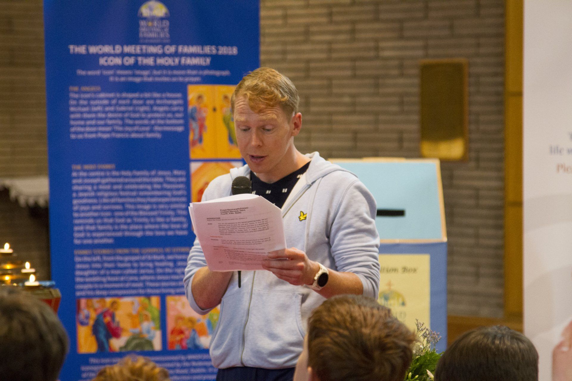 A man is giving a speech in front of a sign that says the world meeting of families