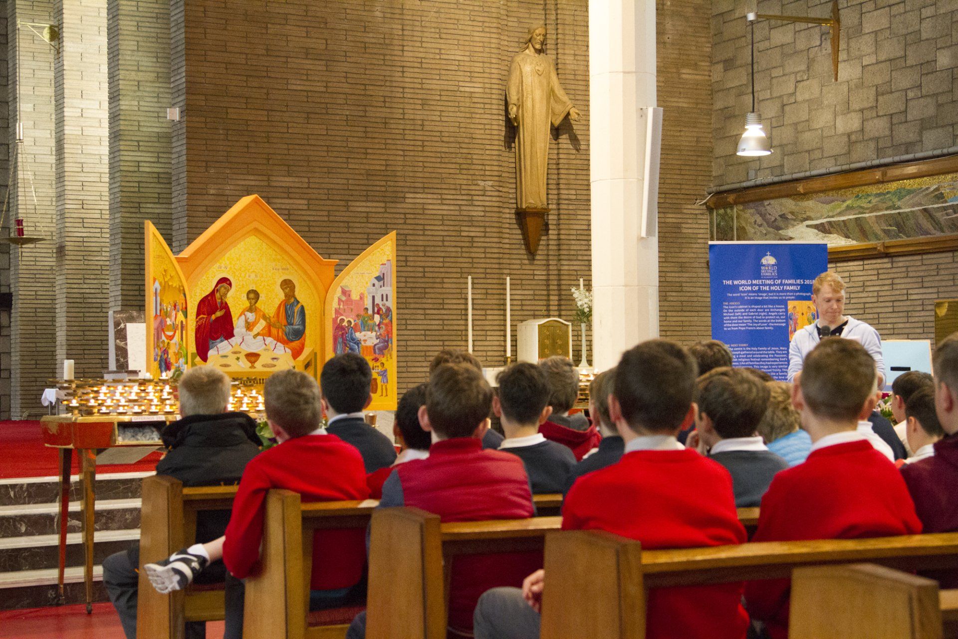 A group of children in red jackets are sitting in a church.