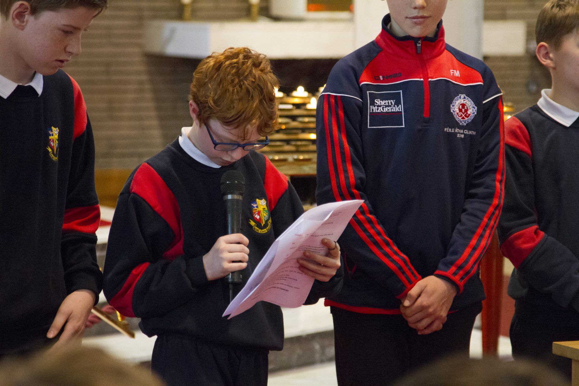A boy in a red and black jacket is reading a piece of paper