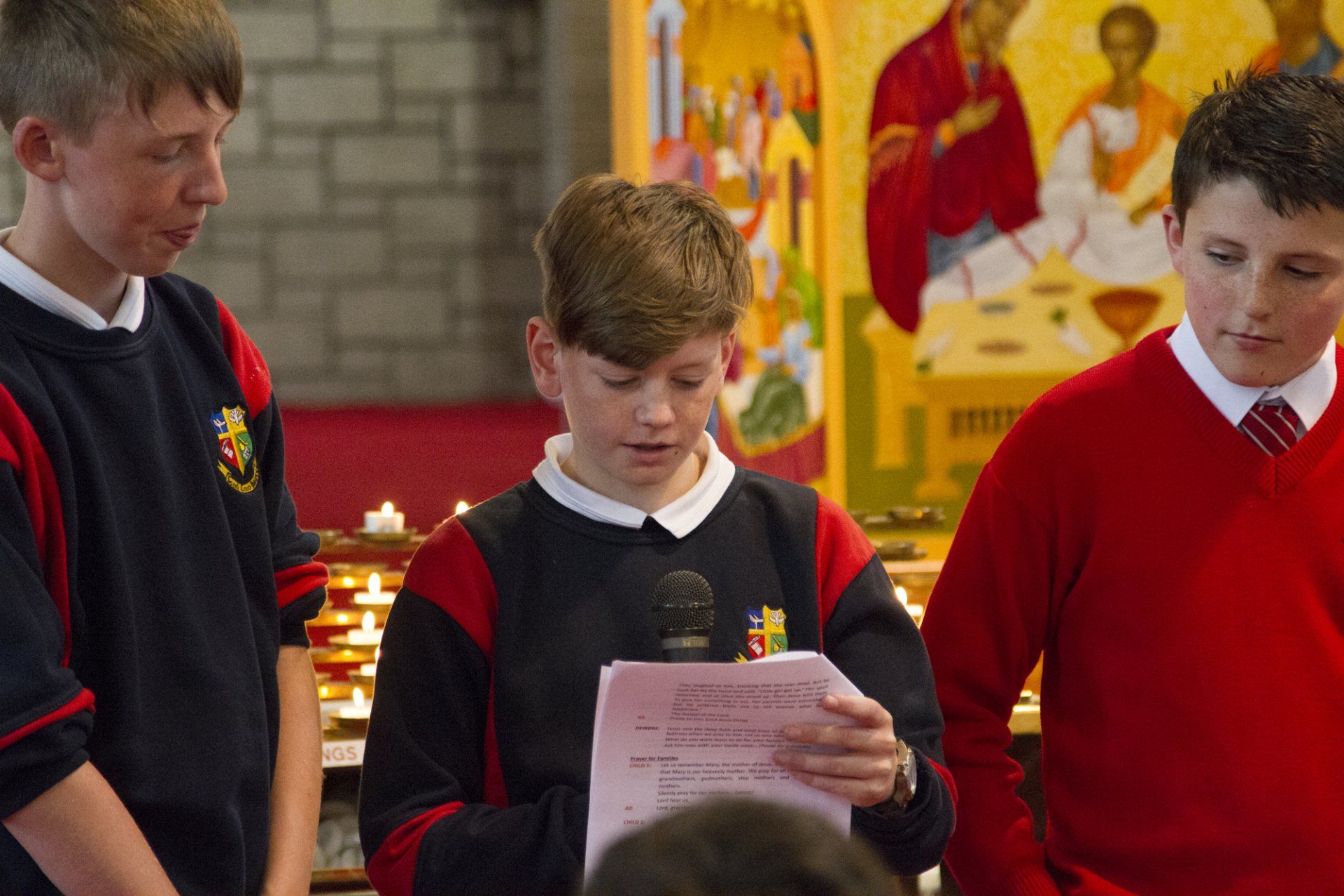 A group of young boys are standing in front of a microphone in a church.