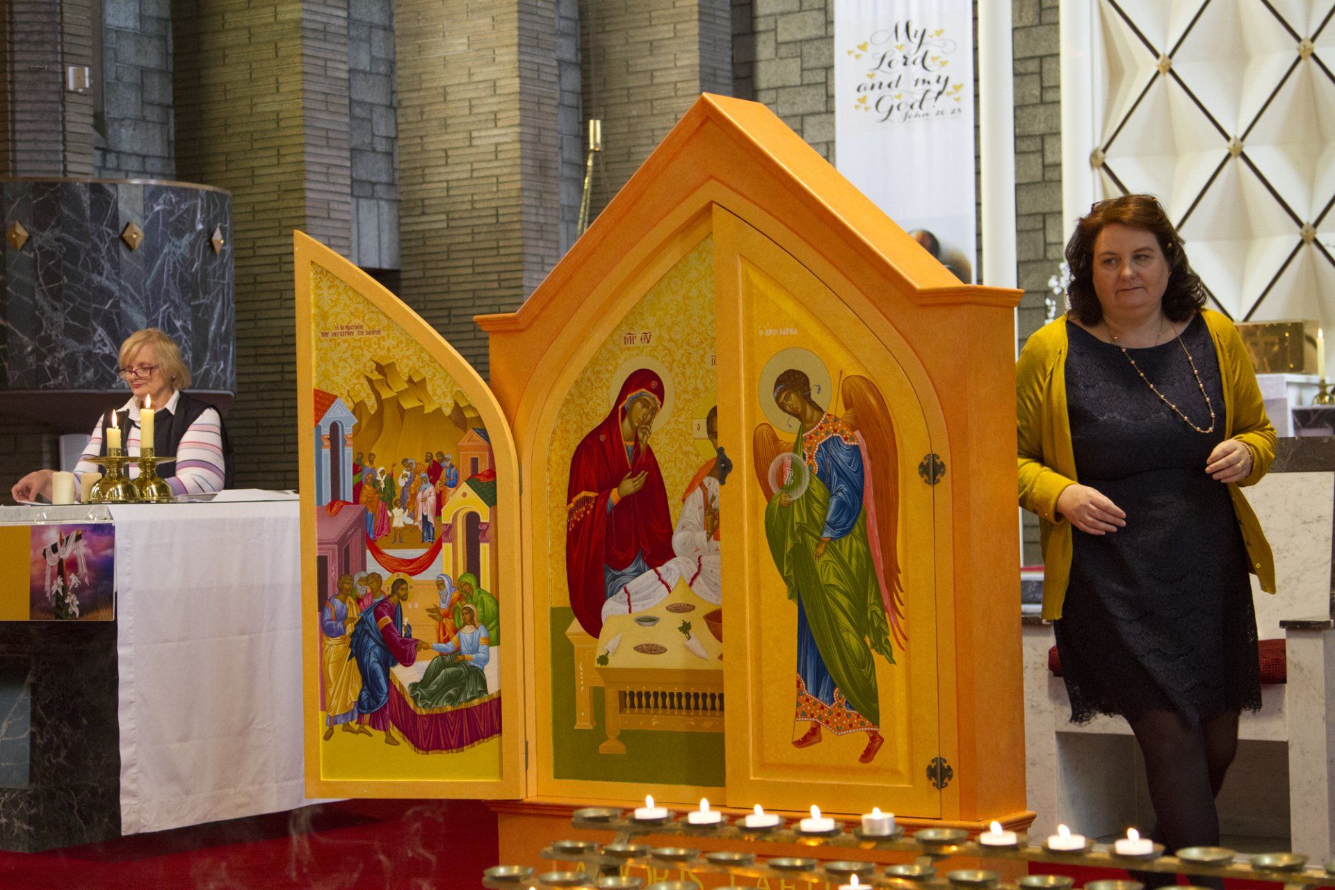 A woman is standing in front of an altar in a church.
