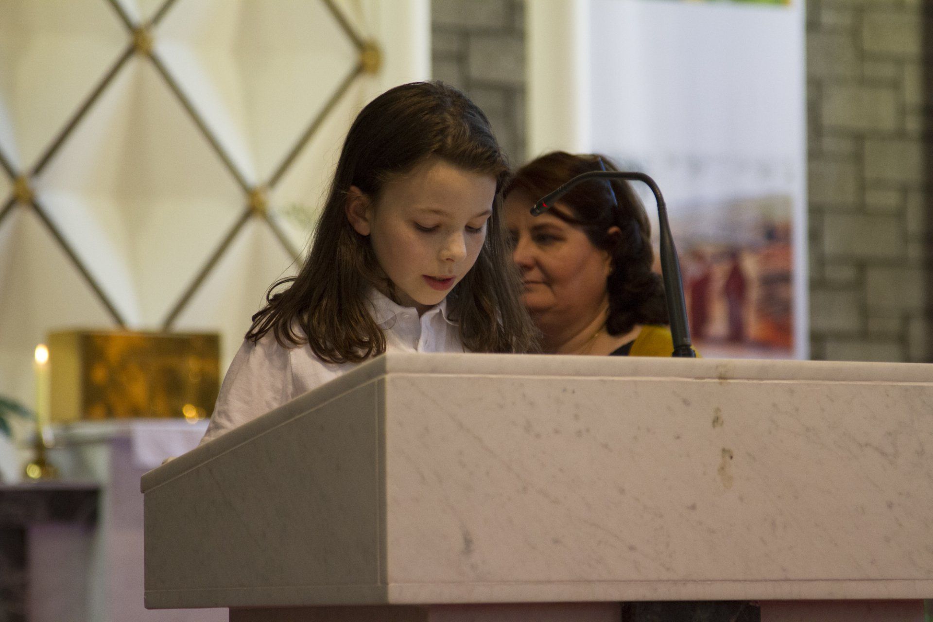 A little girl is sitting at a podium in a church.