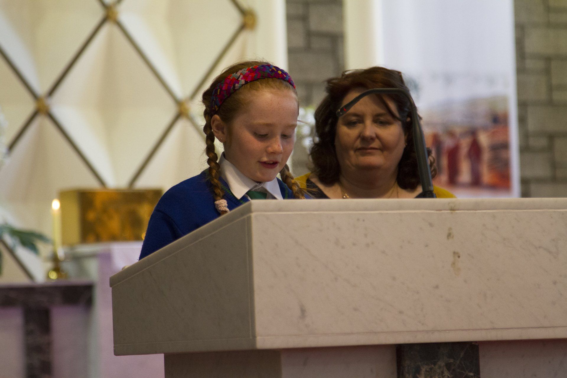 A woman and a girl are standing at a podium in a church.