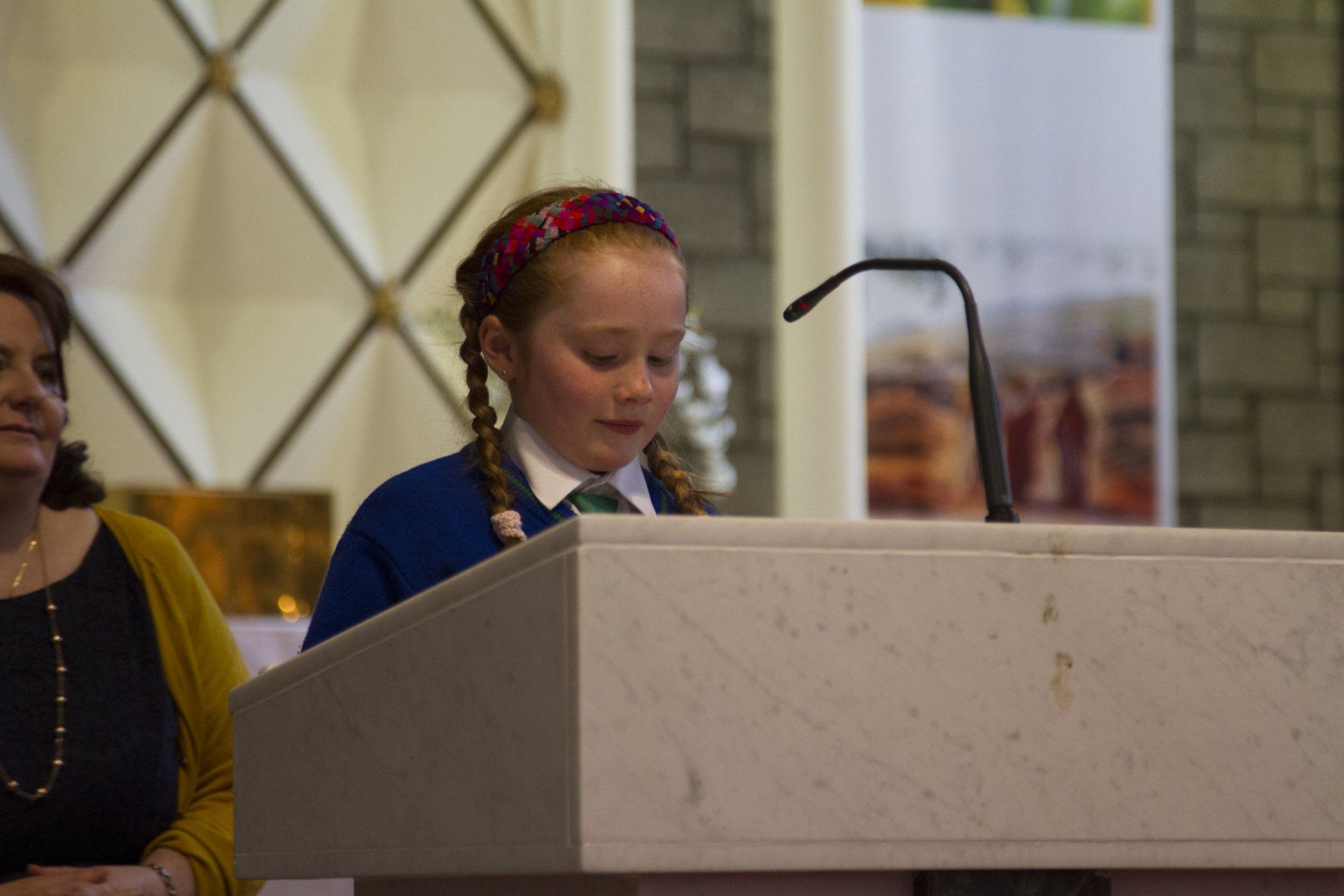 A little girl is standing at a podium in a church.
