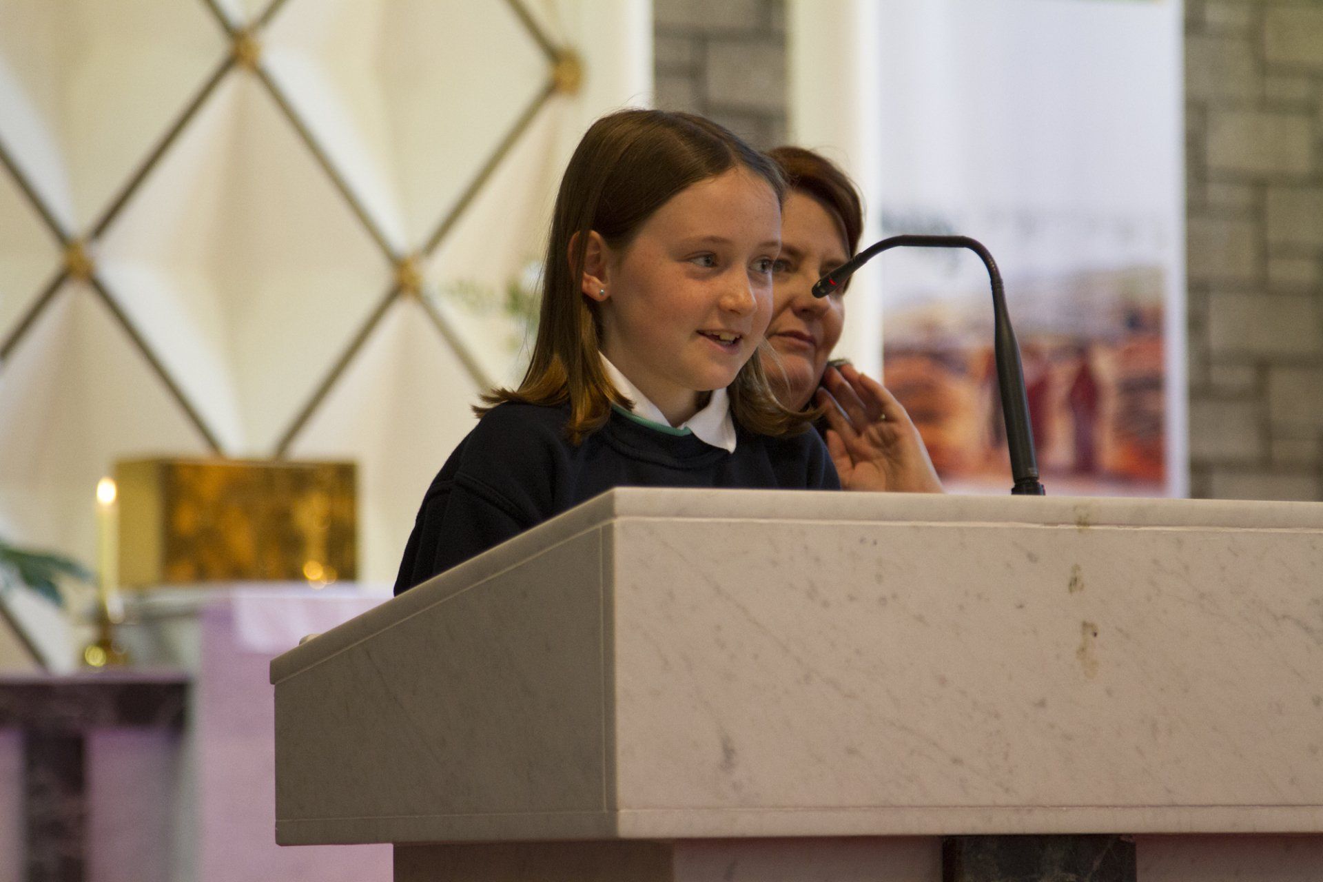 A young girl is standing at a podium in front of a microphone.