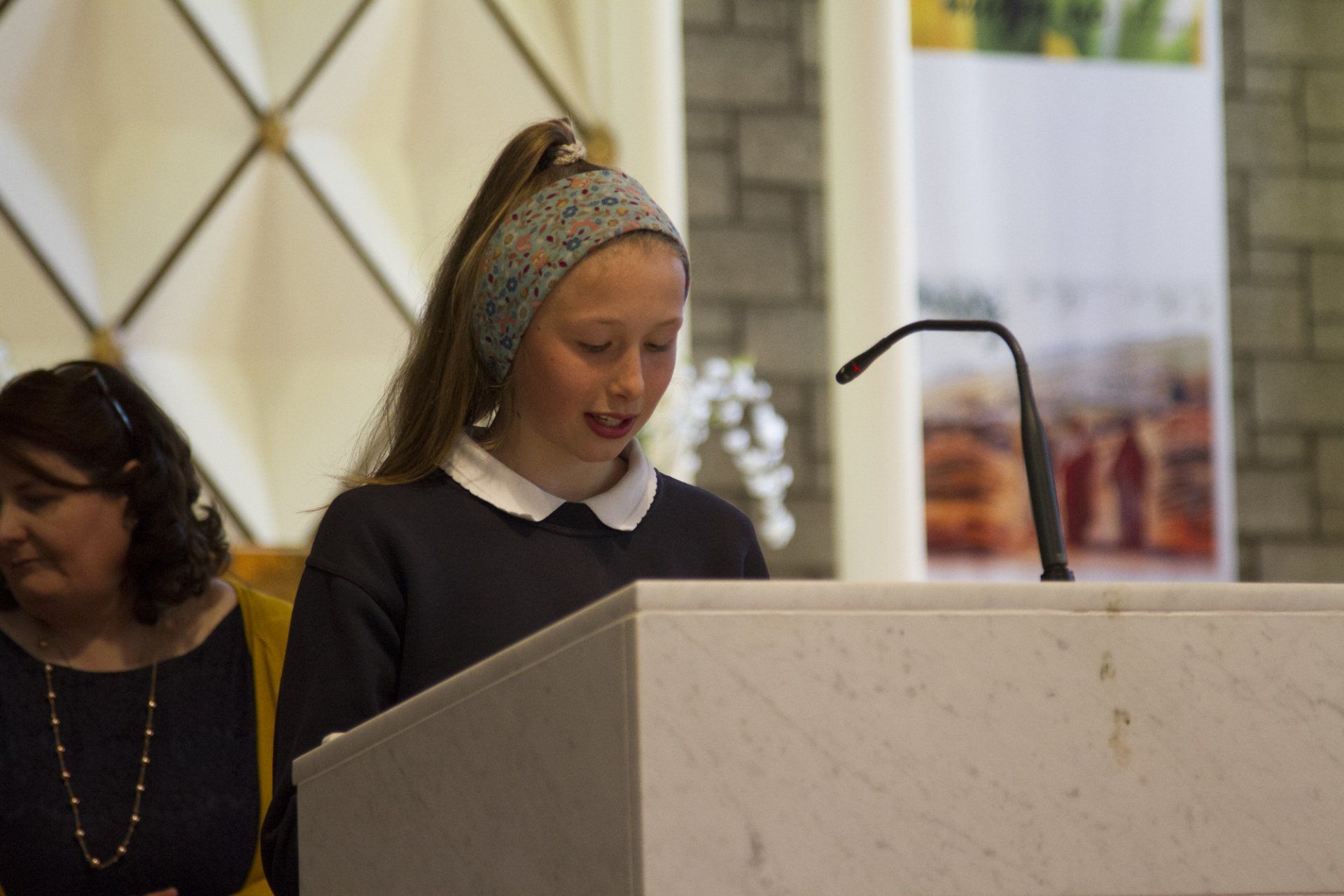 A young girl is standing at a podium in a church.