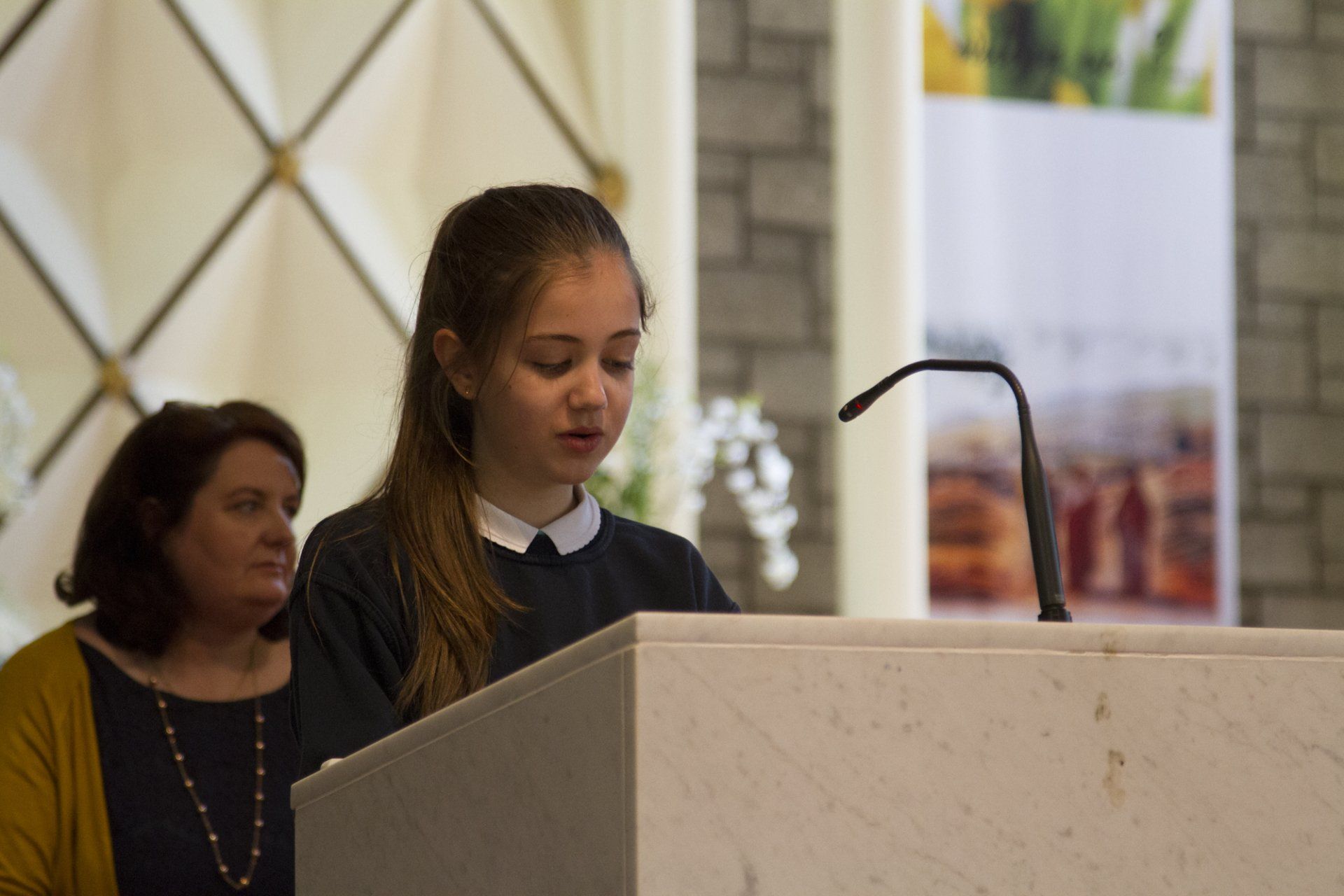A young girl is standing at a podium in a church.