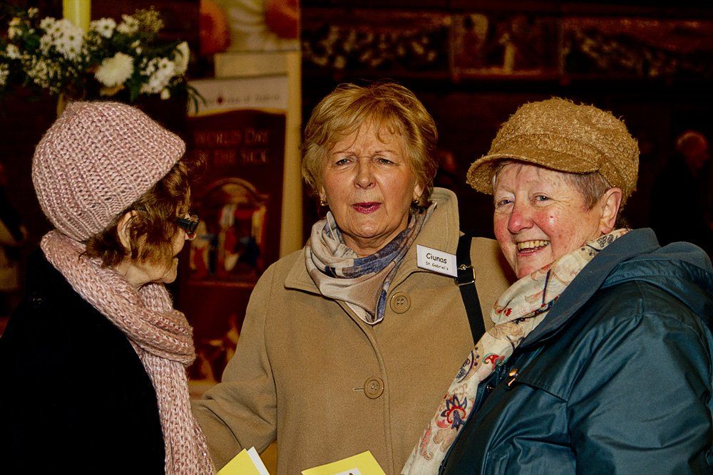 Three women are standing next to each other and smiling.