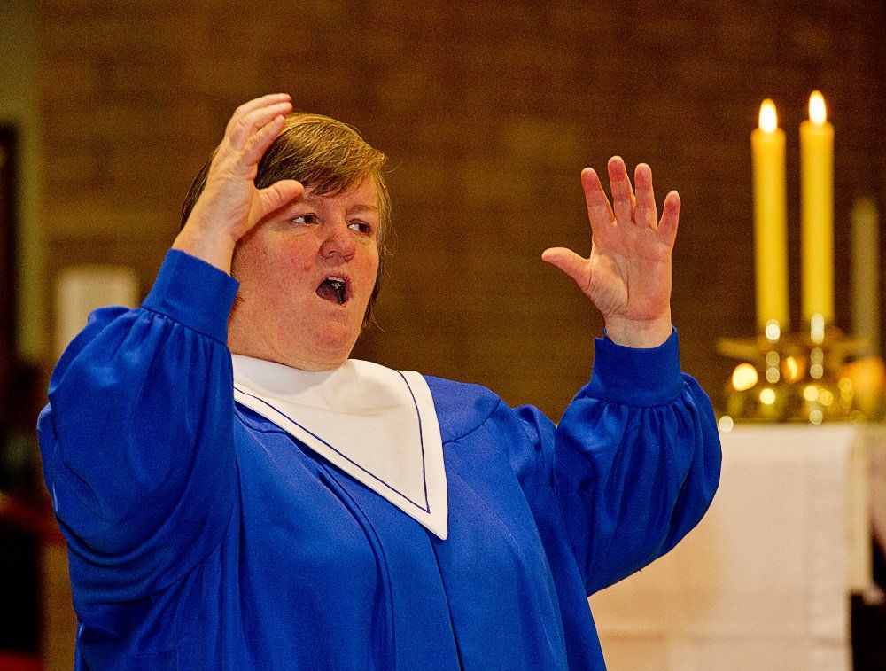 A woman in a blue gown is singing in front of candles
