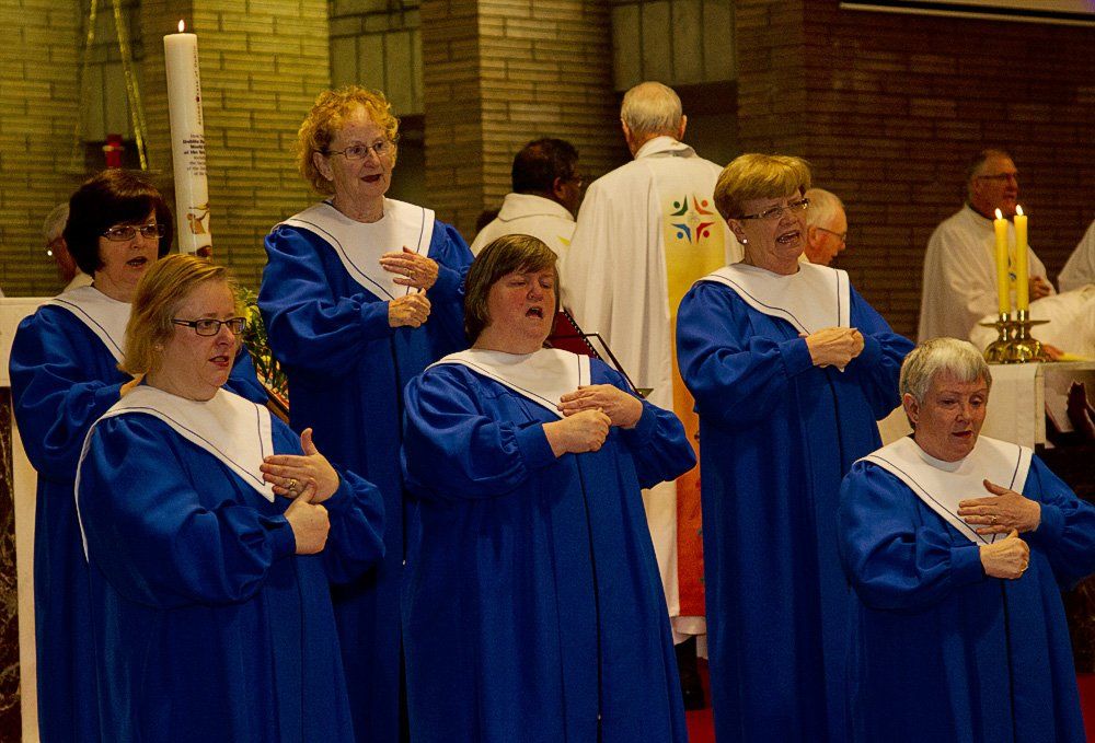 A group of women in blue robes are singing in a church