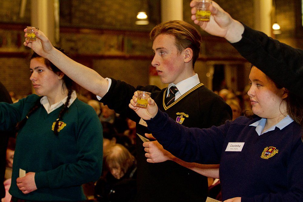 A group of young people are raising their glasses in the air
