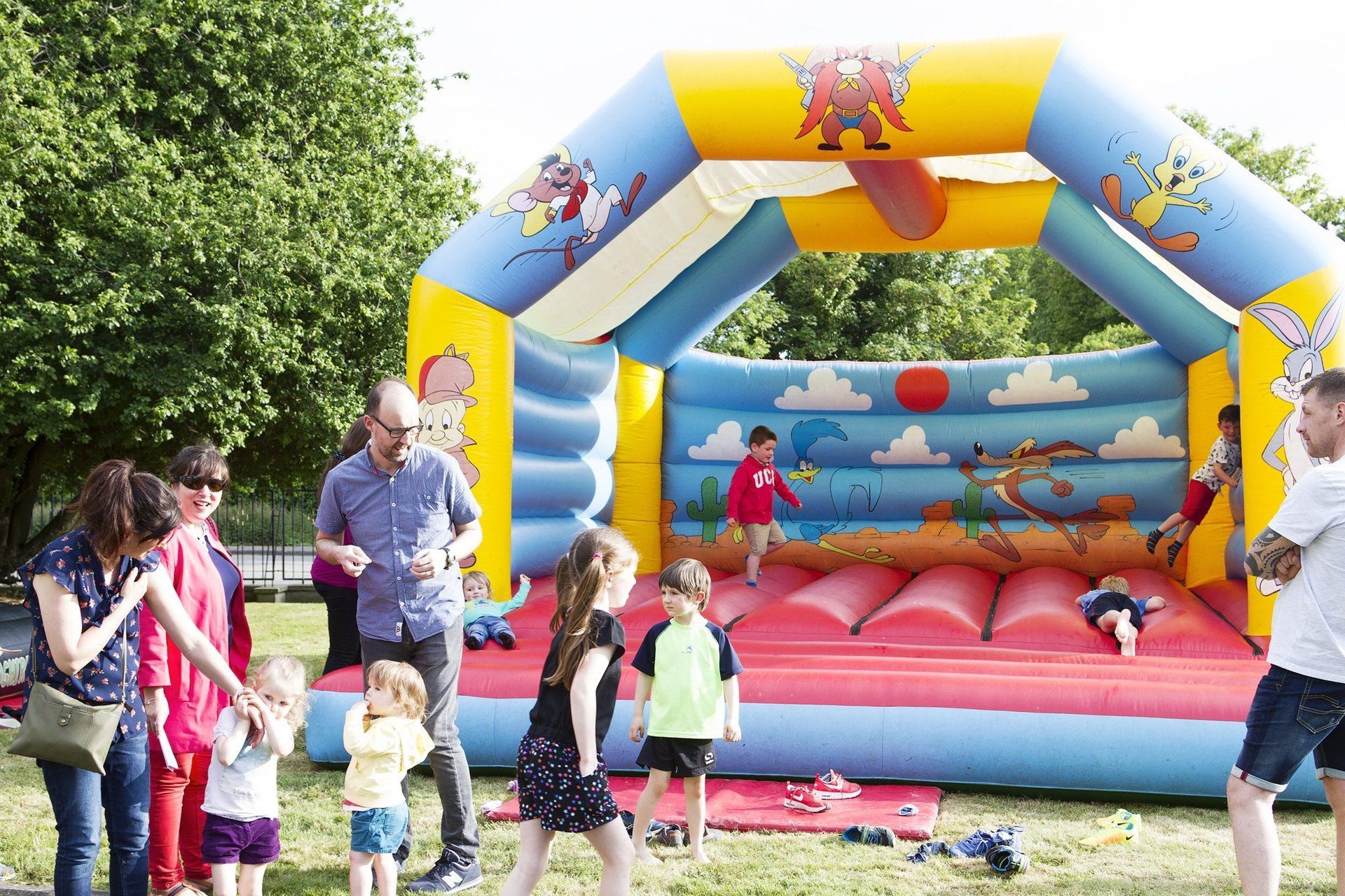 A group of people are standing around a bouncy house.
