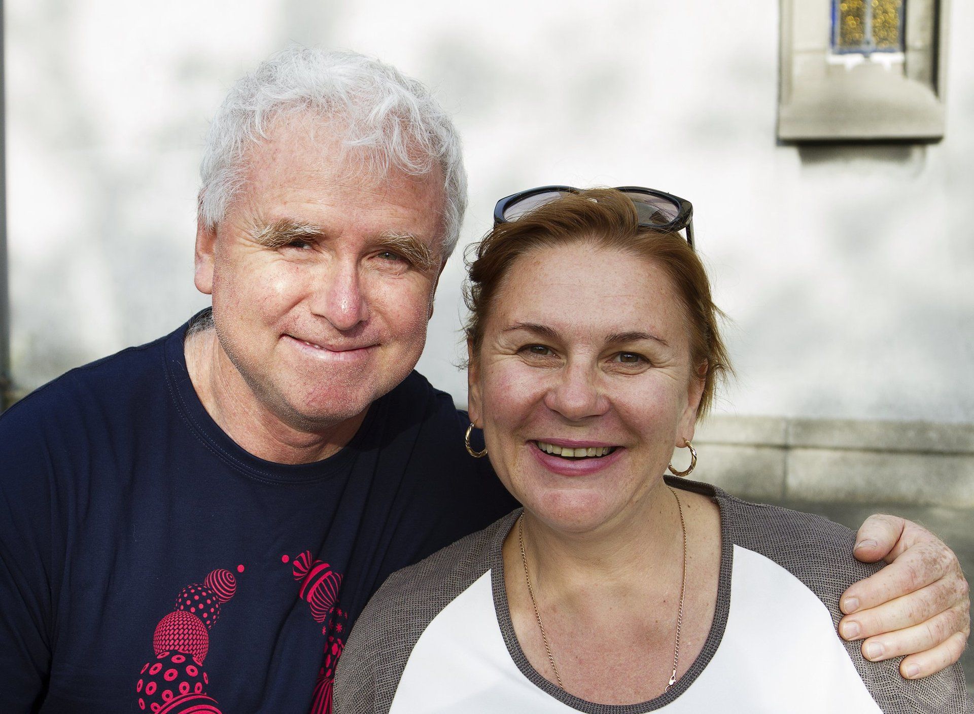 A man and a woman are posing for a picture and smiling for the camera.