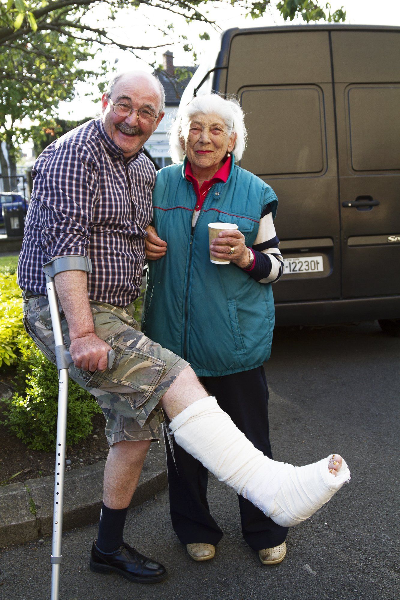 A man with crutches is standing next to a woman with a cast on her leg