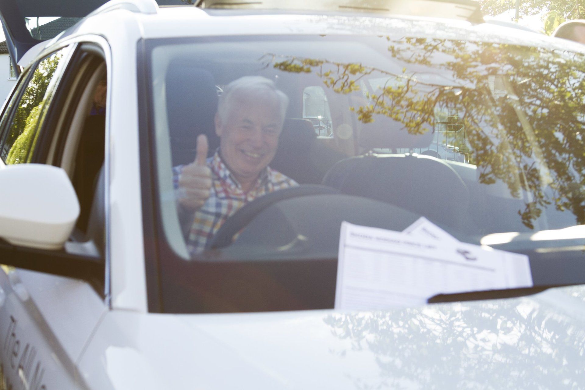 A man is giving a thumbs up while sitting in a car.
