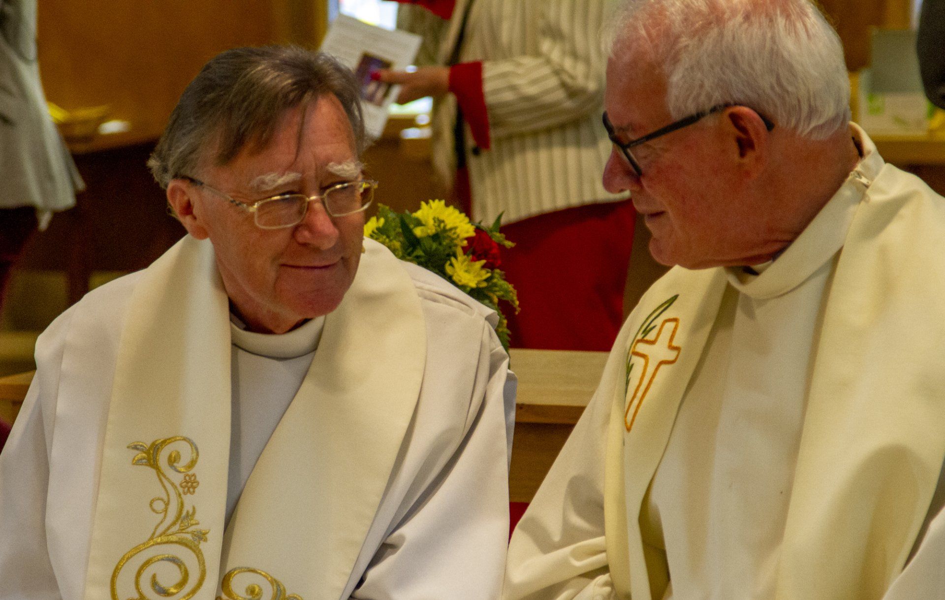 Two priests are talking to each other in a church.