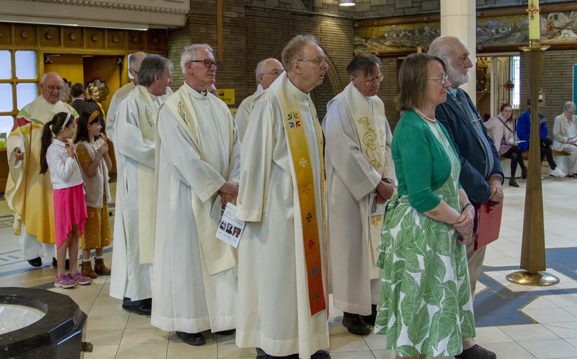 A group of priests are standing in a line in a church.