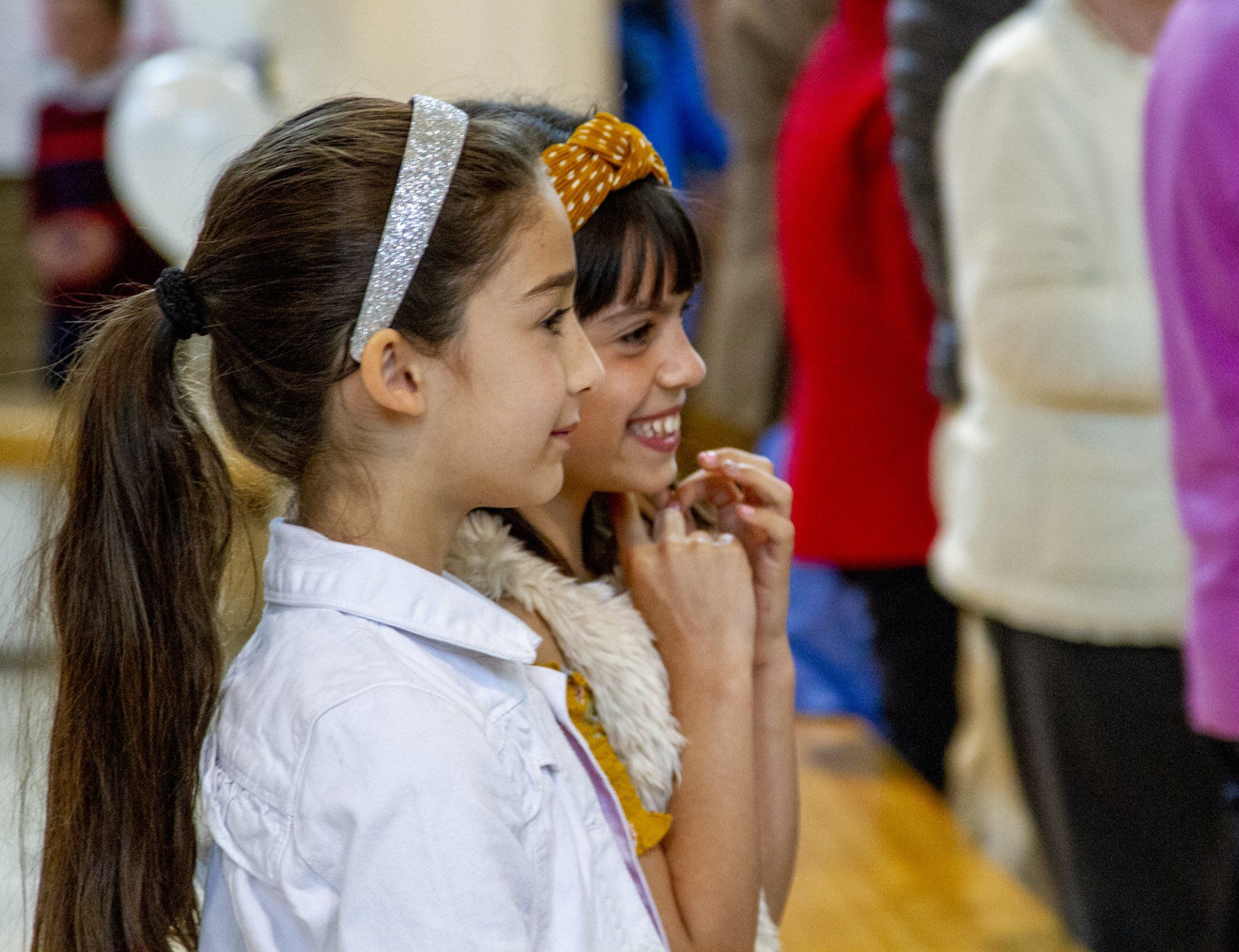 Two young girls are standing next to each other in a crowd.