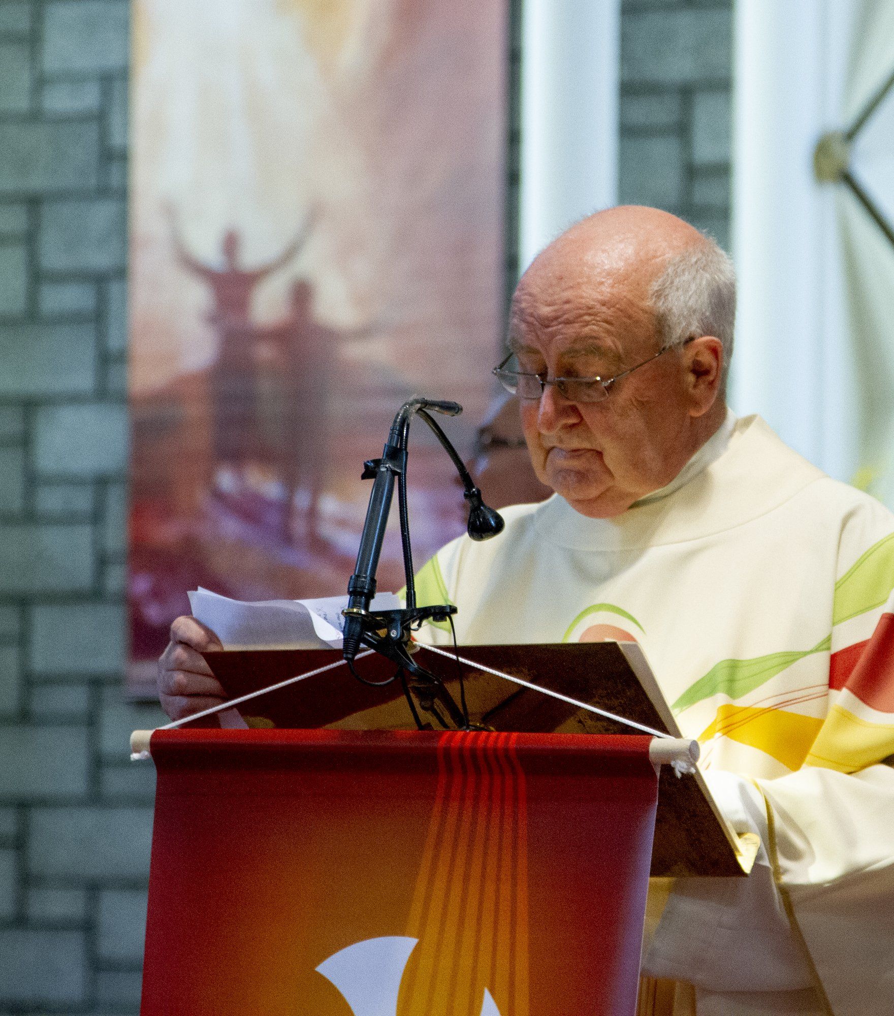 A man stands at a podium reading a book