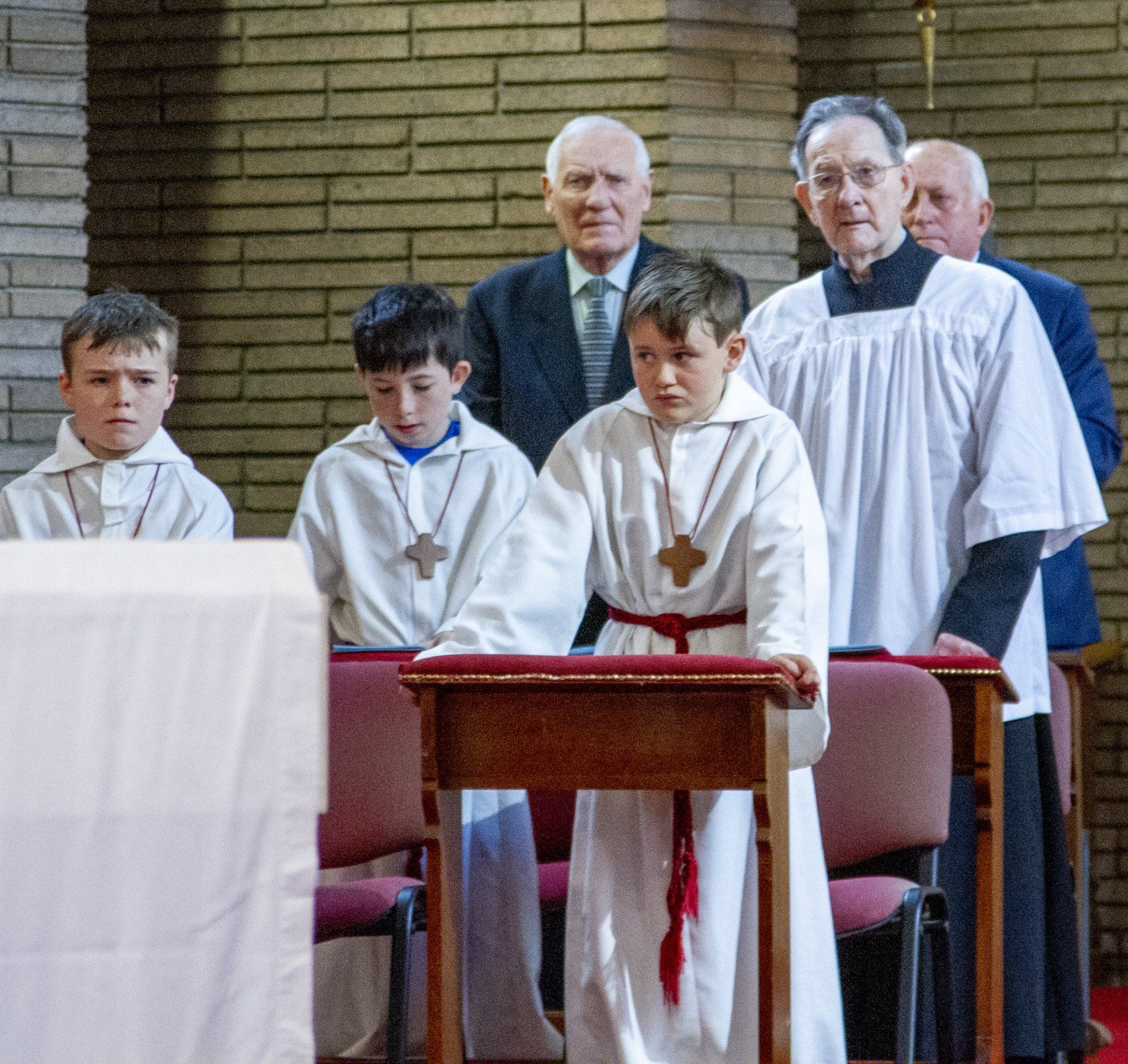 A group of priests and boys are standing around a podium in a church