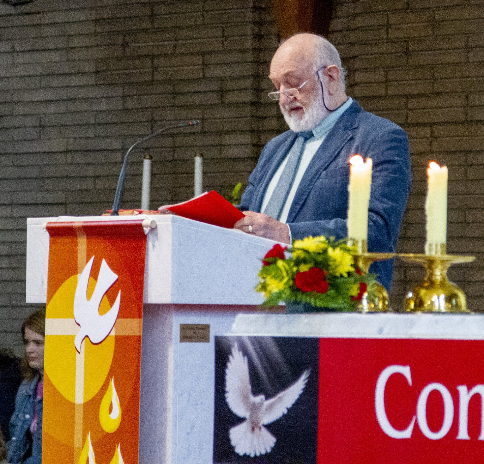 A man stands at a podium in front of a sign that says con