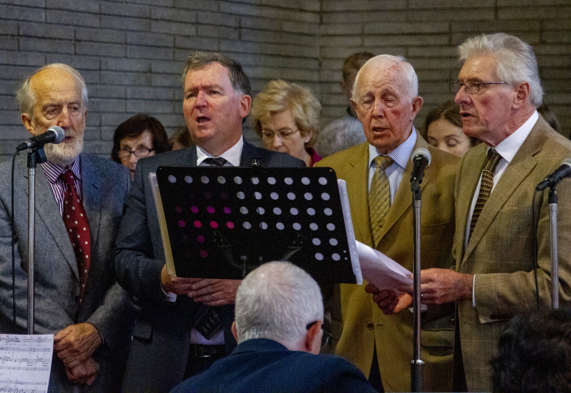 A group of men are singing into microphones in a church.