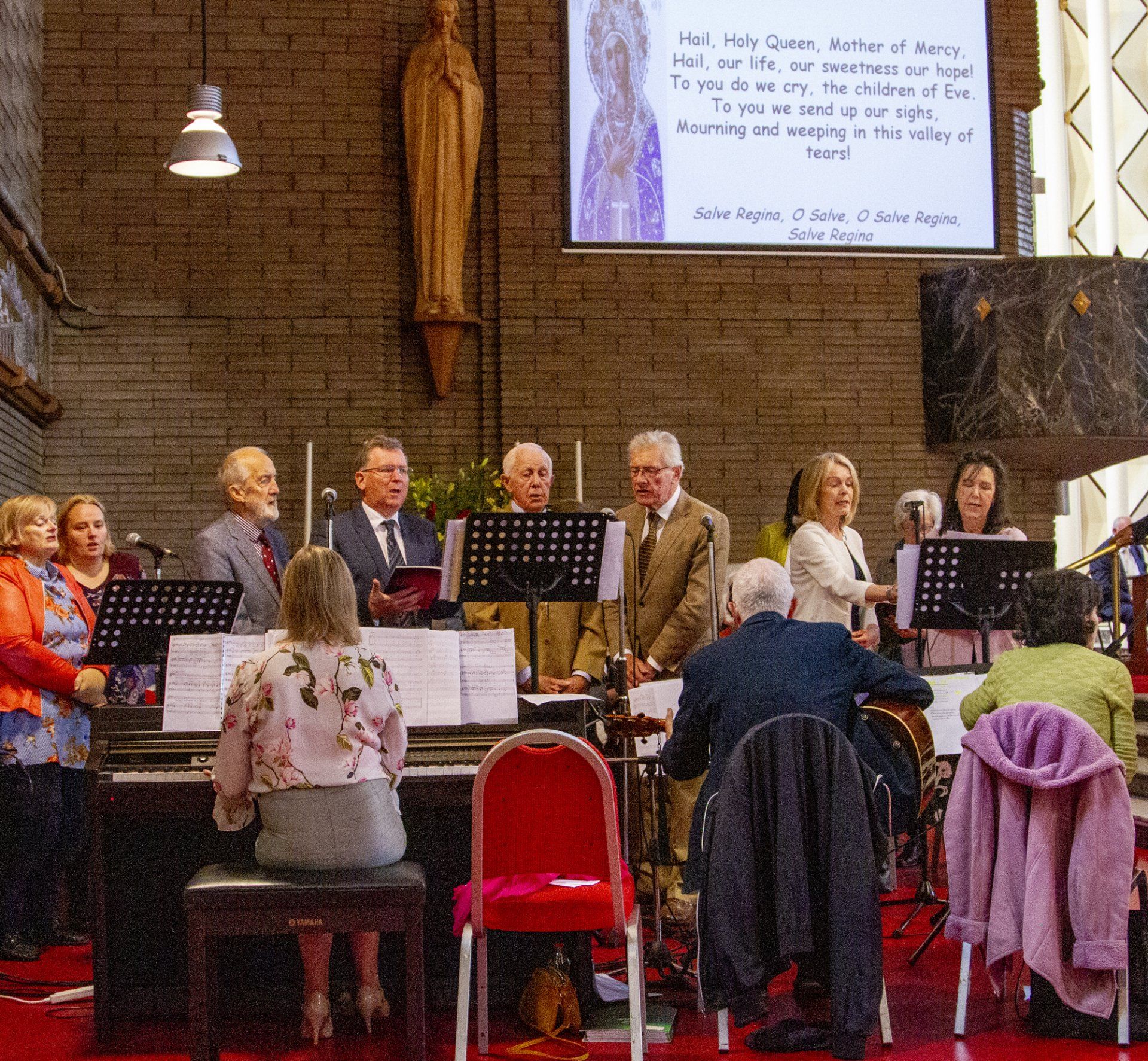 A group of people playing instruments in front of a large screen