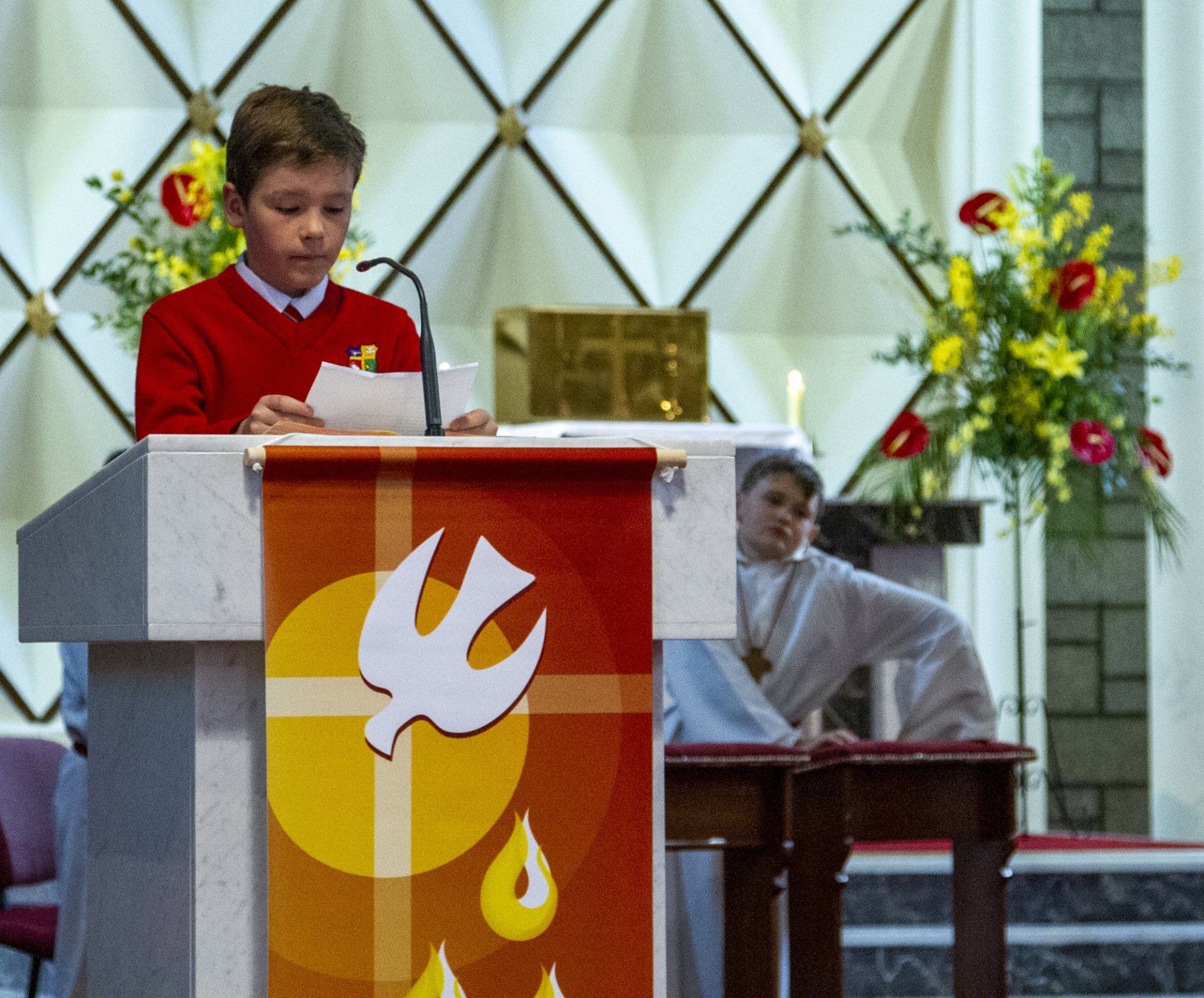 A boy stands at a podium with a dove on it