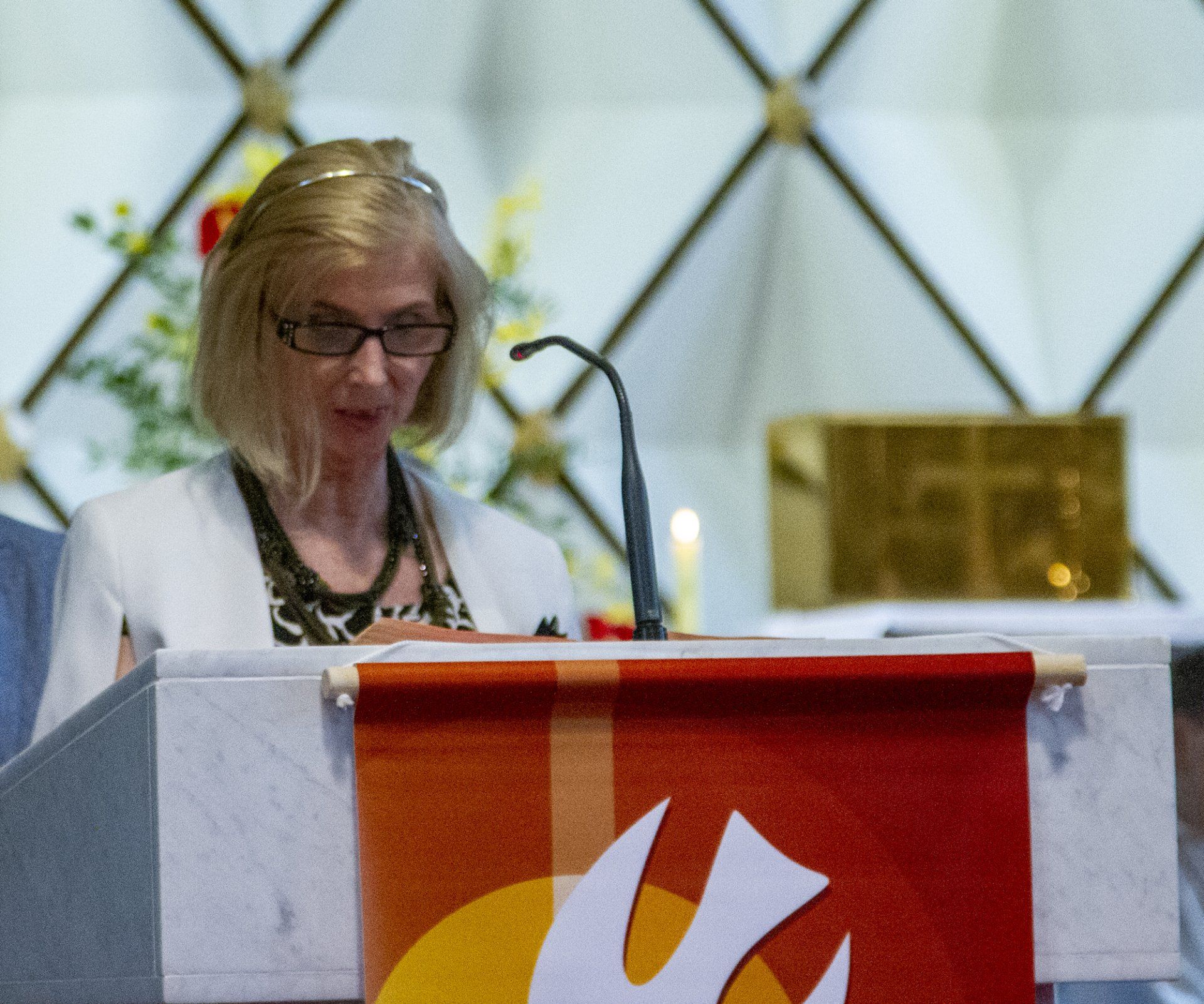 A woman stands behind a podium with a dove on it