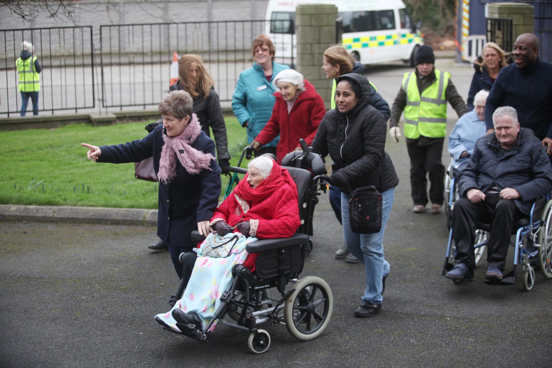 A group of people are walking with a woman in a wheelchair.