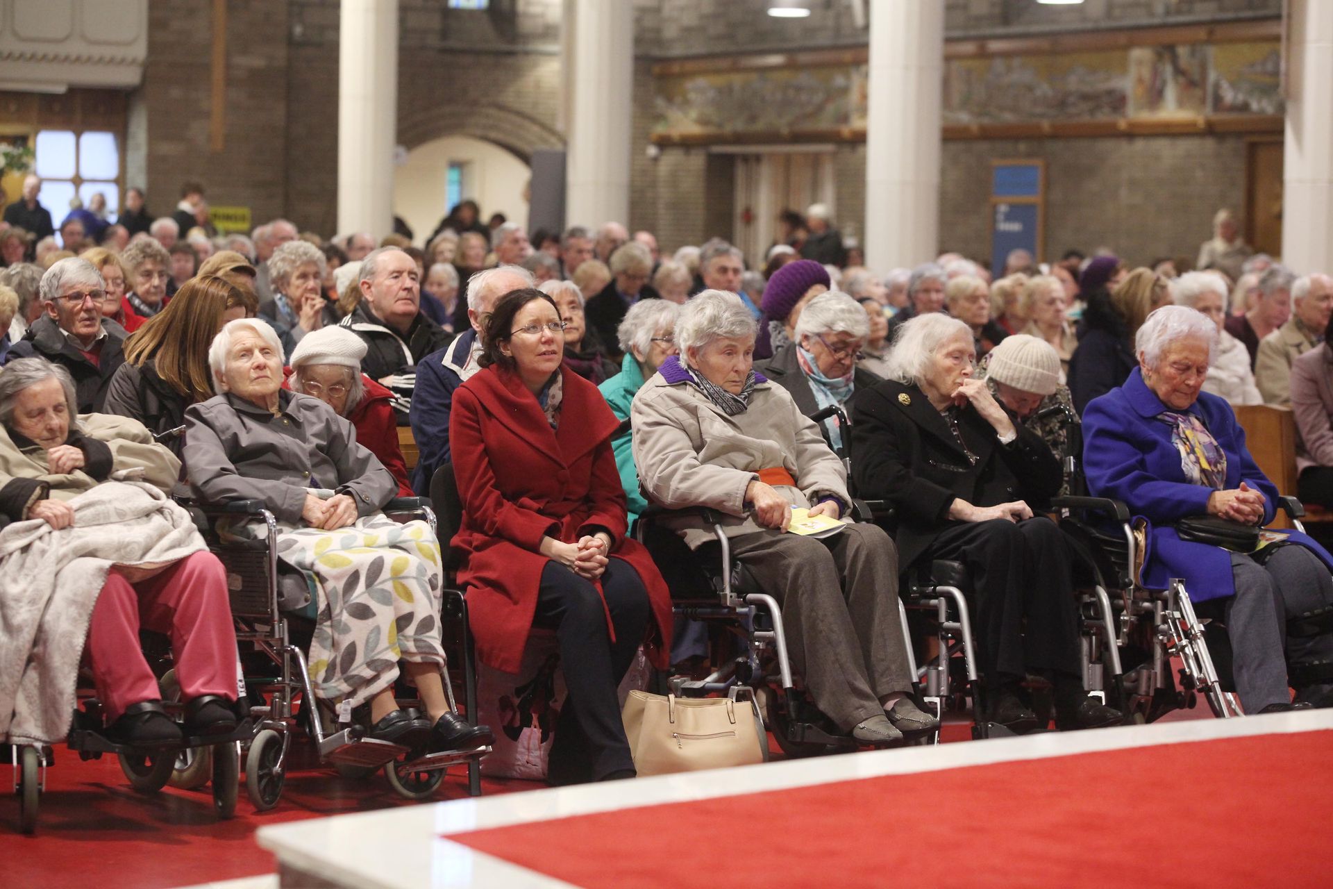 A large group of people in wheelchairs are sitting in a church.