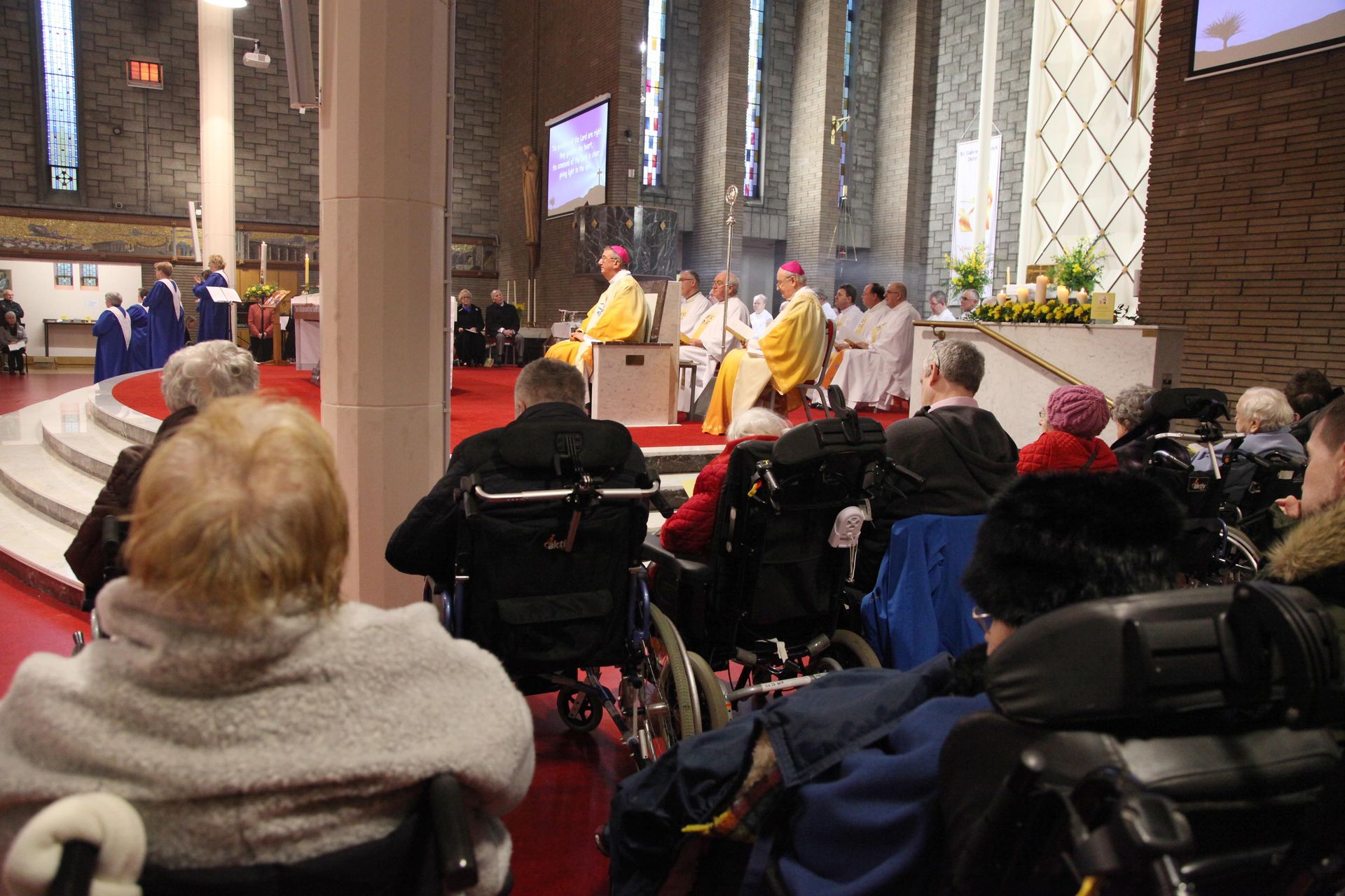 A group of people in wheelchairs are sitting in a church